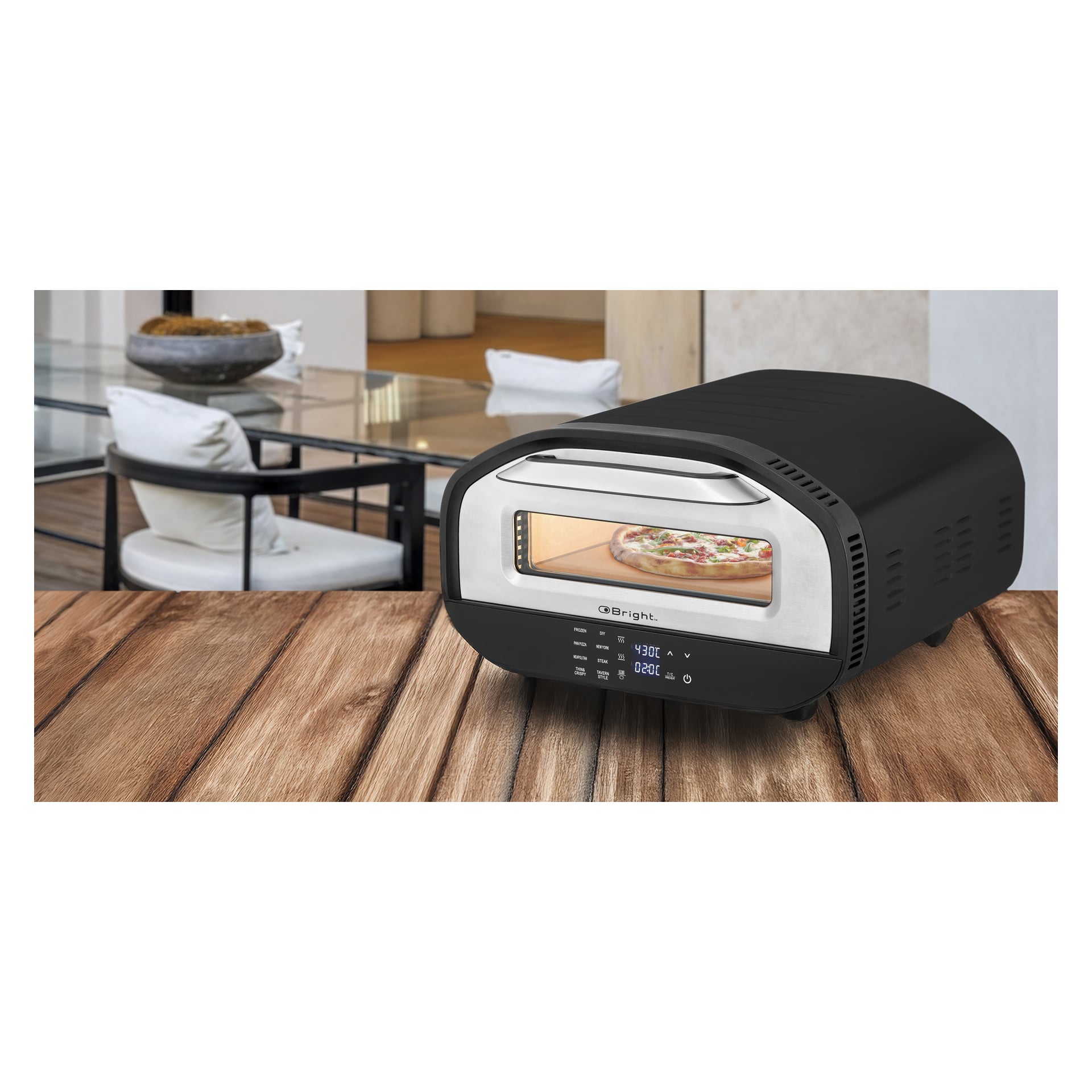 En svart Bright Electric pizzaovn med digital skjerm baker pizza på tre, plassert foran et moderne spiseområde og glassbord.