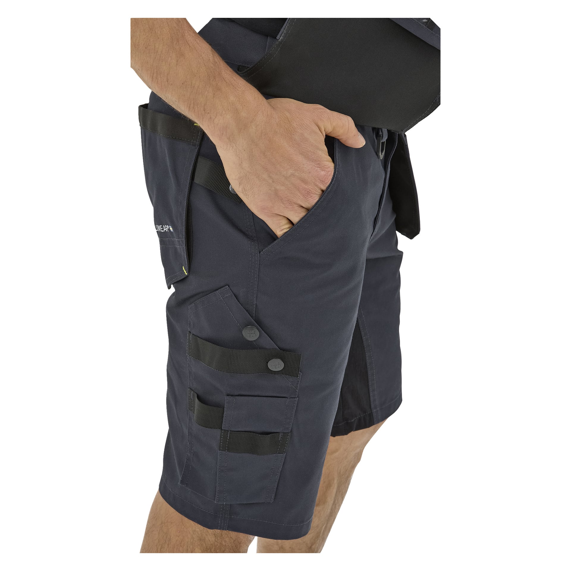 En person i Bluewear Men's Rex arbeidsshorts med flere lommer og knapper, høyre hånd i frontlommen; Bare overkropp og lår synlige.