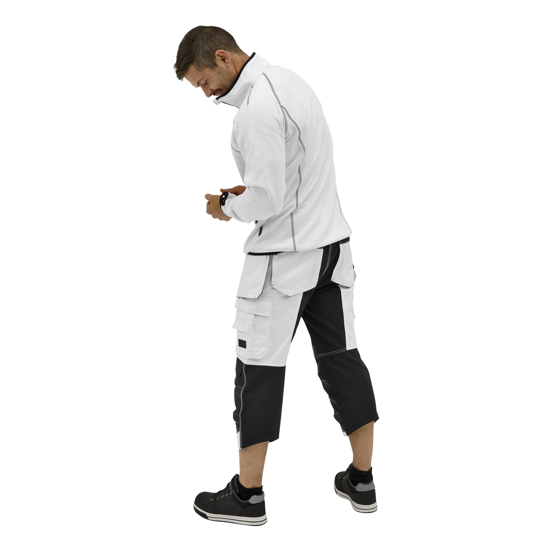 En man i en Bluewear Men's sweater Malte står med ryggen vänd och tittar ner på något i sina händer. Han har svarta sneakers och vita-svarta arbetsshorts.