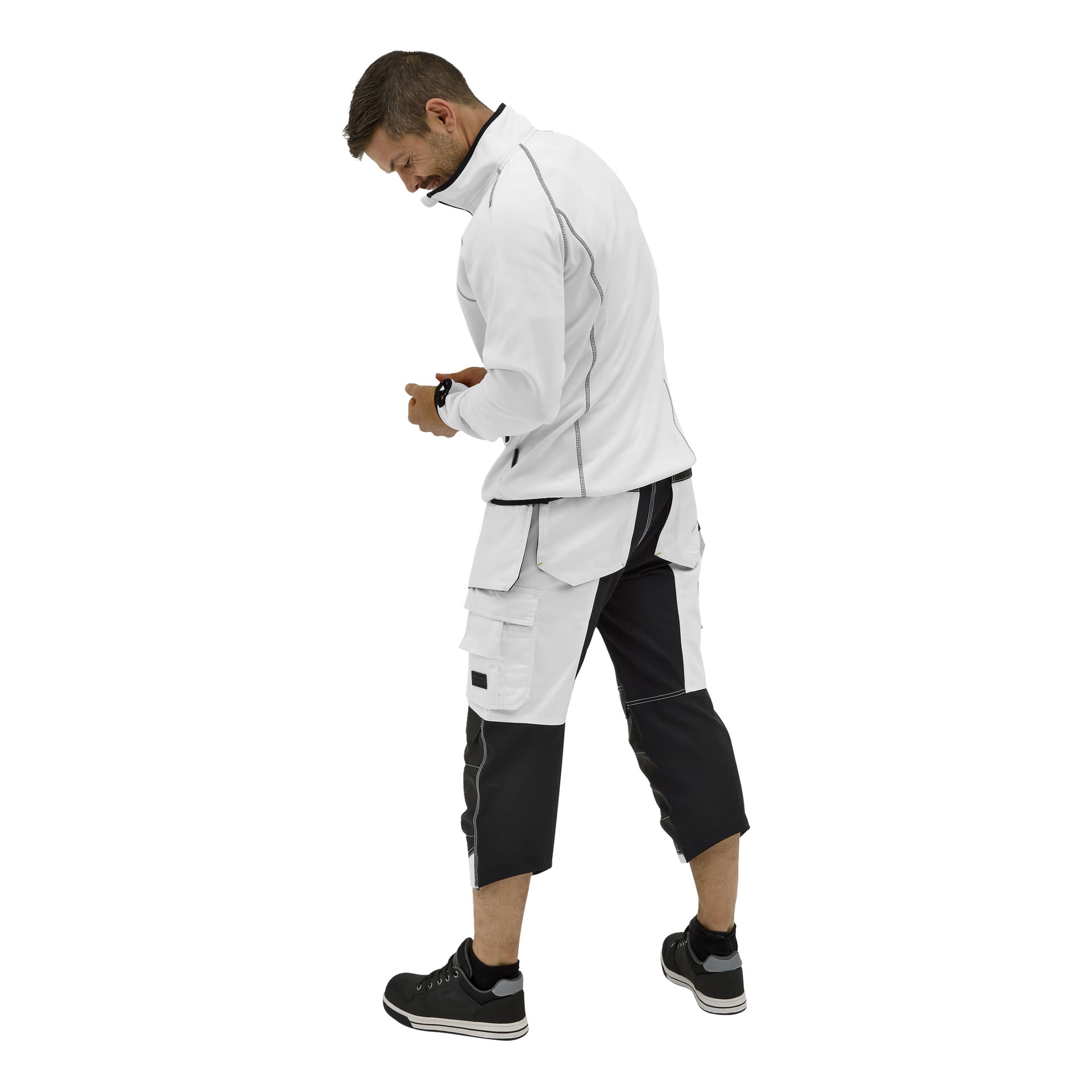 En man, med ryggen vänd, undersöker sin vänstra handled. Han bär en Bluewear Malte-tröja, tvåfärgade arbetsshorts med fickor och svarta sneakers.