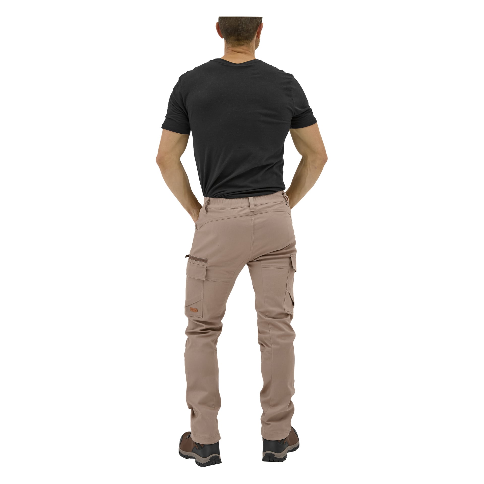 Ein Mann steht mit dem Rücken zur Kamera, trägt ein schwarzes T-Shirt, hellbraune Åsen-Outdoorhosen und schwarze Schuhe, die Hände in die Hüften.