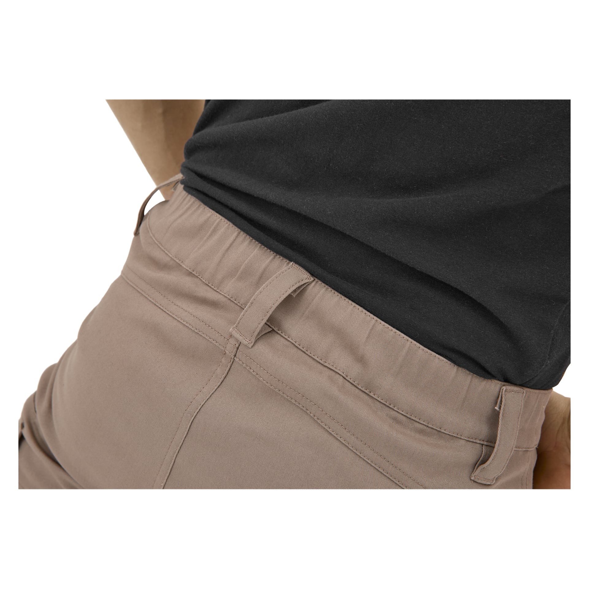 Nahaufnahme einer Person in hellbraunen Kayoba Outdoor Åsen-Hosen mit elastischer Taille, kombiniert mit einem schwarzen Hemd; Taille sichtbar.