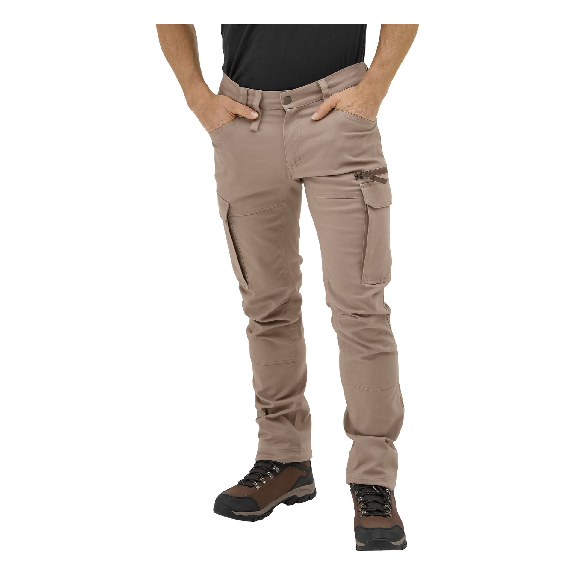 Person trägt beige Kayoba Outdoor Åsen-Hose mit schwarzem T-Shirt, braunen Wanderschuhen; Hände in den Taschen, kurz geschnittene Brust nach unten.