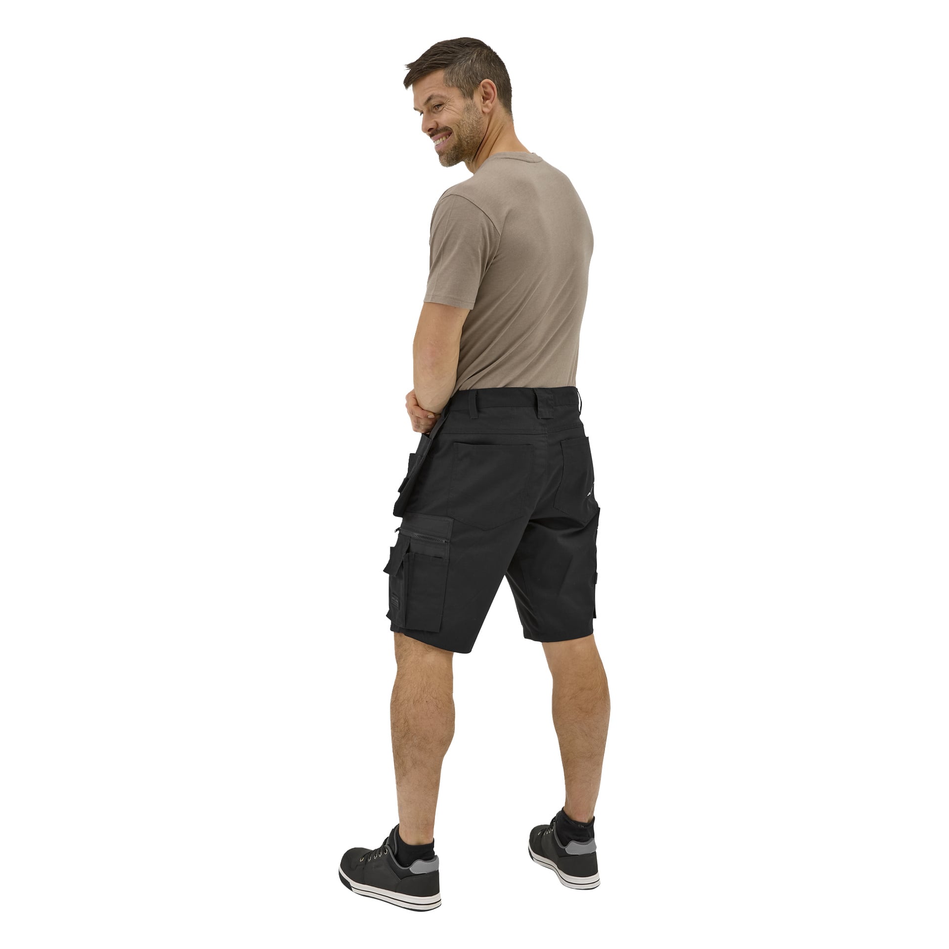 En man vänder sig bort och kastar en blick bakåt. Han har på sig en taupe t-shirt, svarta Bluewear-shorts med sidofickor och svarta sneakers.