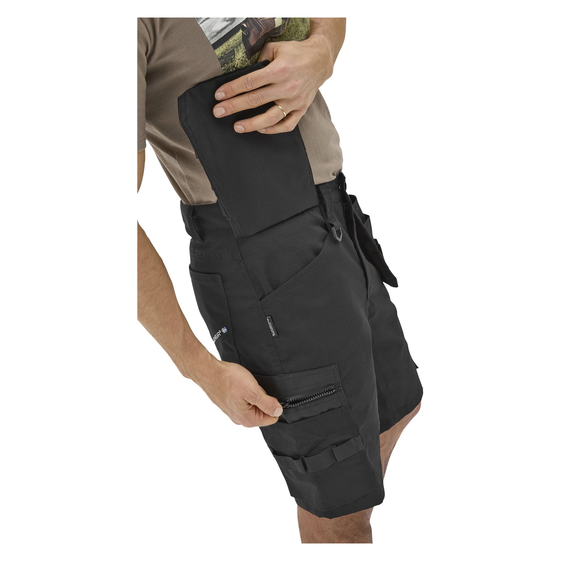 Någon visar den avtagbara fickan på svarta Bluewear Micke arbetsshorts för herrar med flera fickor, dragkedjor och öglor.
