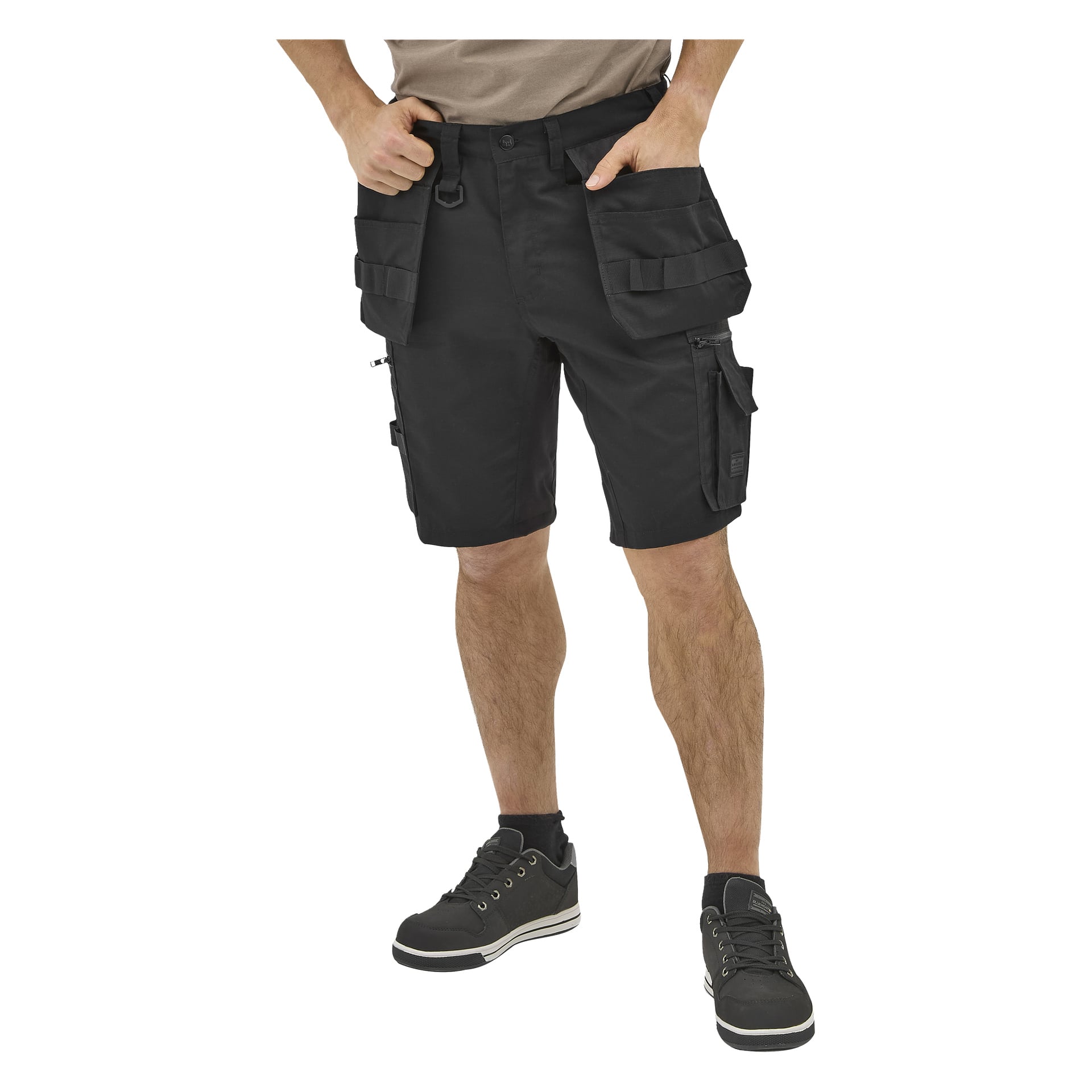 Man bär Bluewear Micke arbetsshorts för herrar med många fickor, remmar, dragkedjor och svarta sneakers. Benen synliga från knäna och neråt.