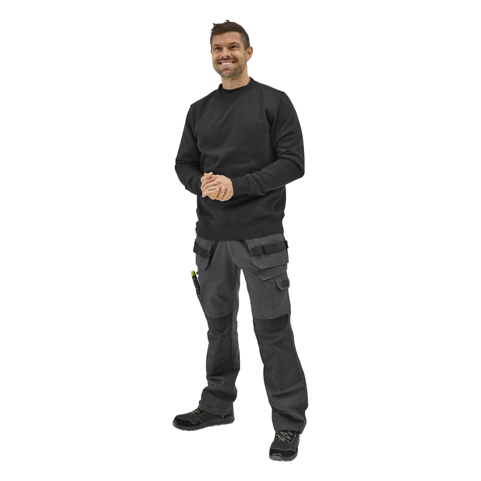 En smilende mann med kort hår folder hendene, kledd i en Bluewear Noa-genser, cargo-arbeidsbukser og svarte arbeidssko.