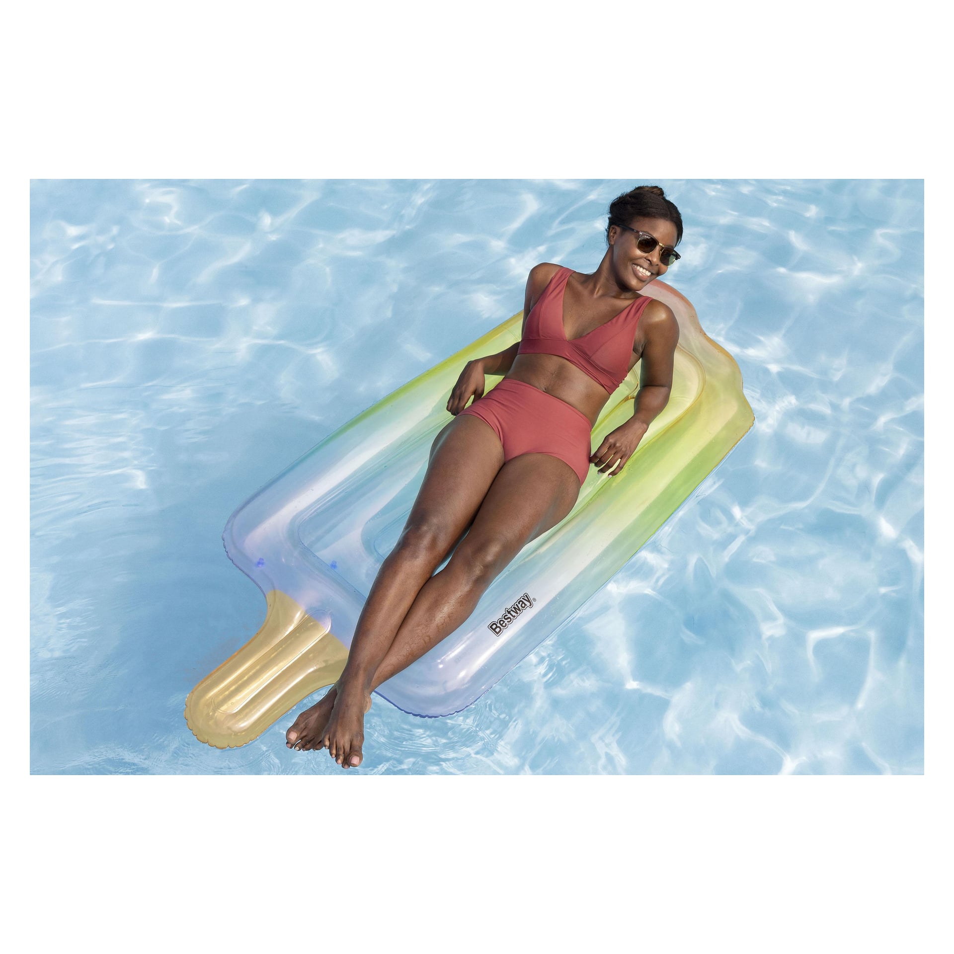 En kvinna med solglasögon ligger på en Bestway solstol medan den flyter i en klar blå pool.