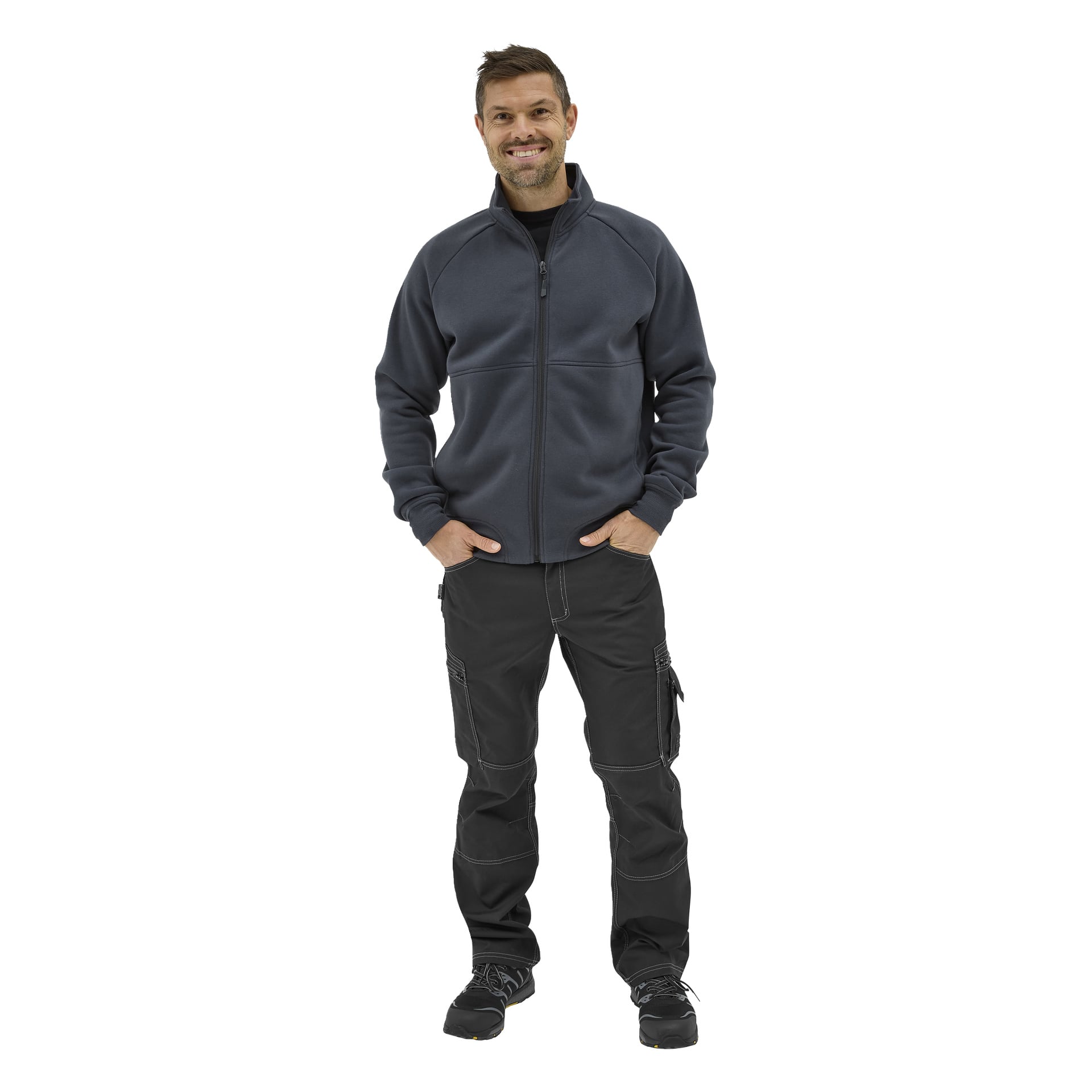 En man ler, bär "Bluewear Men's Sweater Atlas" med händerna i fickorna på sina svarta cargobyxor, tillsammans med en mörk dragkedjajacka och svarta sneakers.