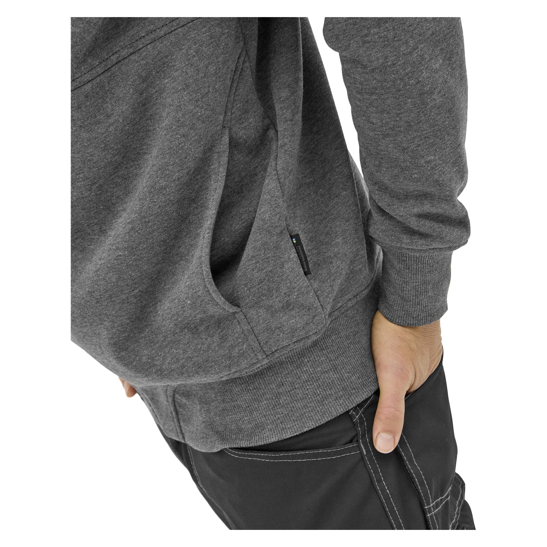 Męski sweter Bluewear Atlas w kolorze ciemnoszarym modelowany jest z czarnymi spodniami, jedną ręką w kieszeni, drugą na biodrze, a tułów widoczny.
