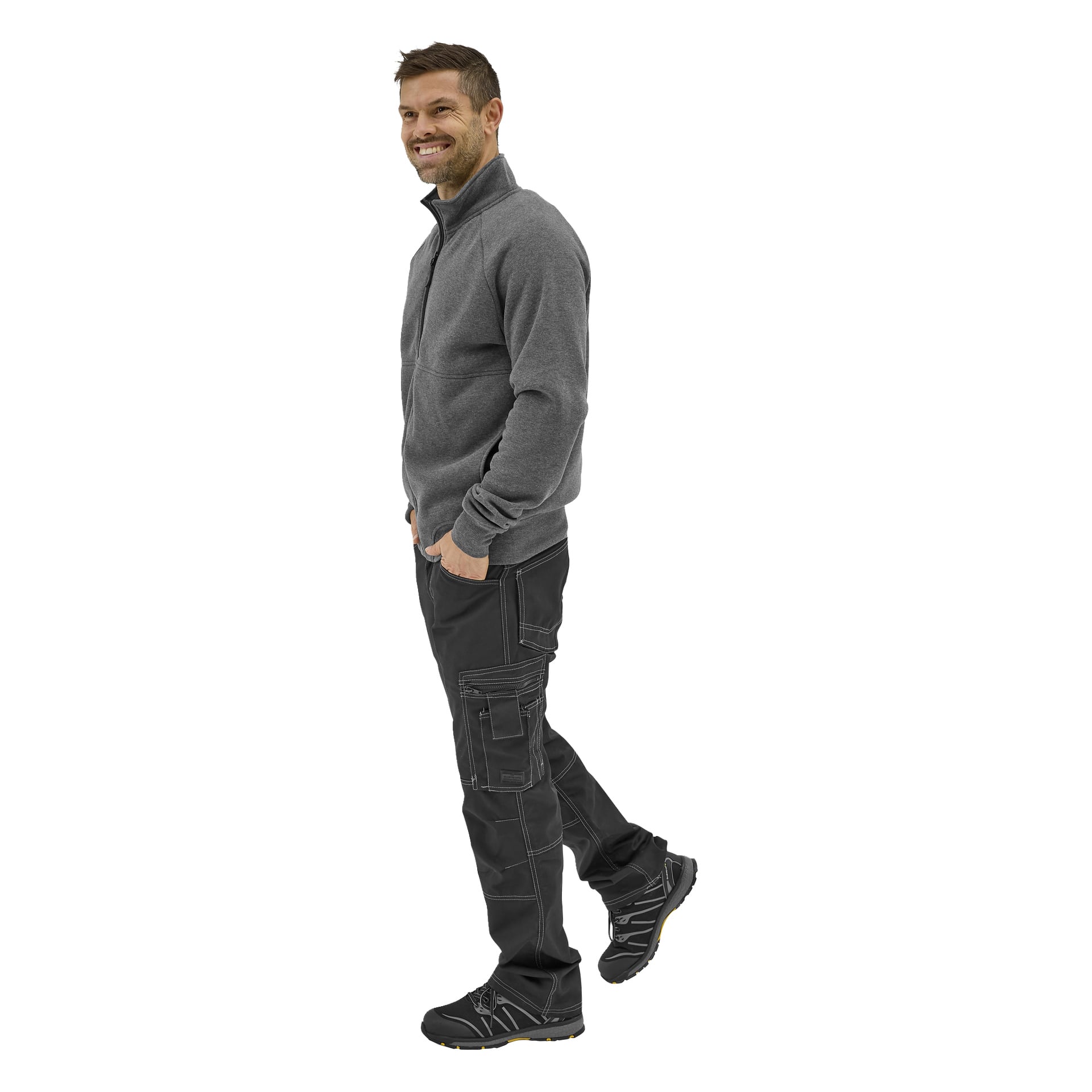 En leende man med kort hår och ansikten till vänster, klädd i en grå Bluewear Atlas-tröja, svarta cargobyxor och svarta sneakers.