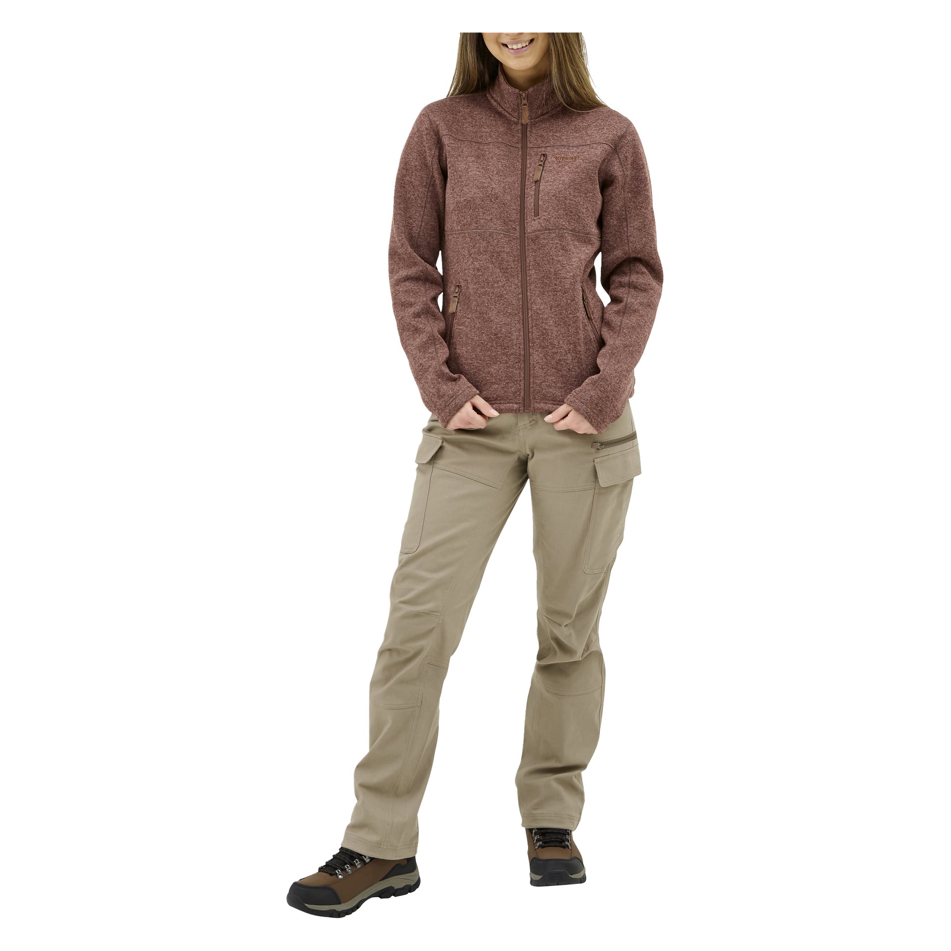 En person står med händerna i fickorna, ler och bär "Damstickad fleece-tröja MALÅ av Kayoba Outdoor."