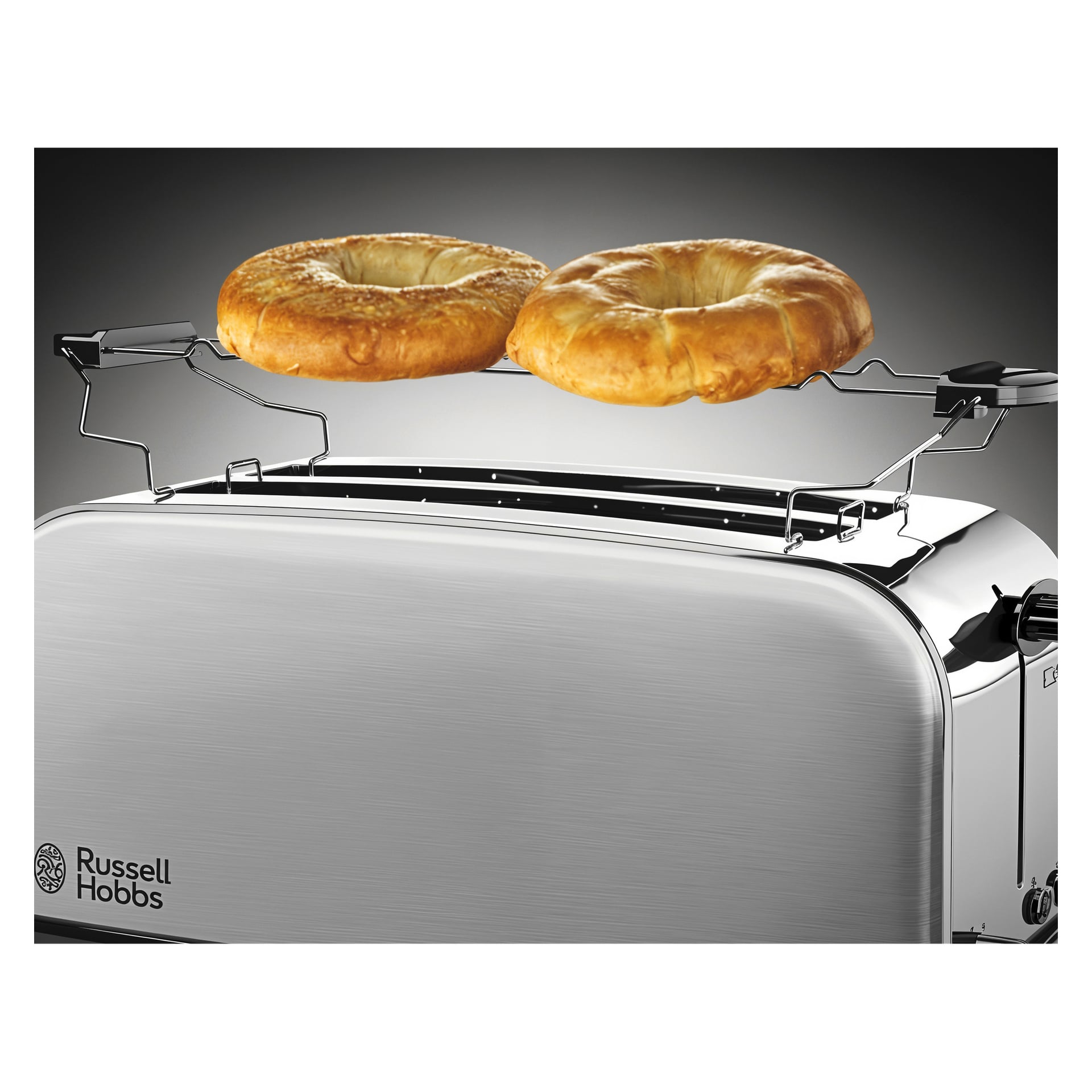 To bagels står på en varmerist over sporene på en Russell Hobbs 4-skives brødrister, med en mørk bakgrunn bak.