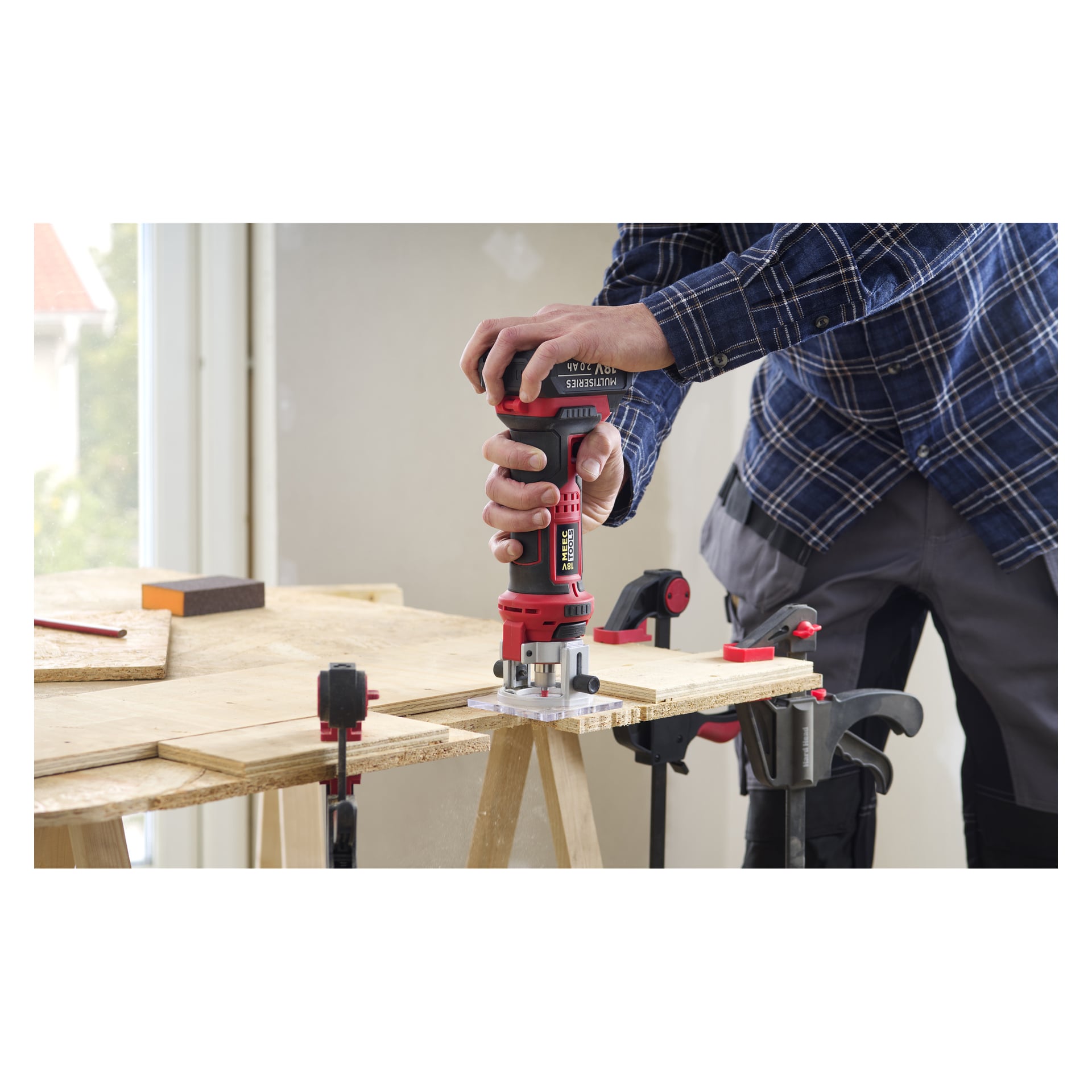 Ktoś wyciąga krawędź drewnianej deski przymocowanej do stołu warsztatowego za pomocą Meec Tools ML-18V HOME 500; Materiały są z tyłu.
