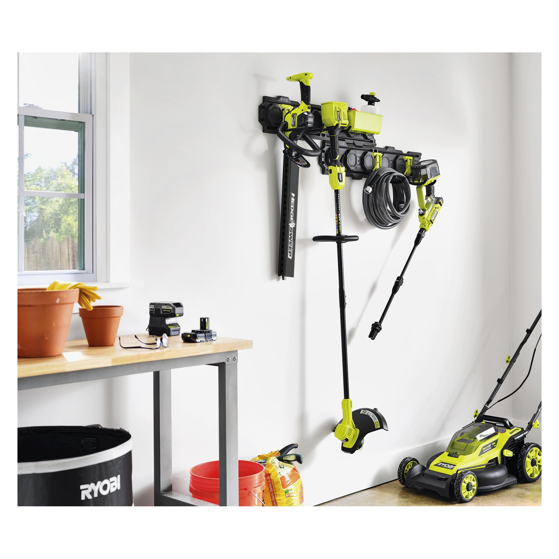 Ryobis LINK RSLWPK-7PC Starter Kit er pent plassert på en vegghylle i et solrikt rom, med verktøy, potter, jord og bord i nærheten.
