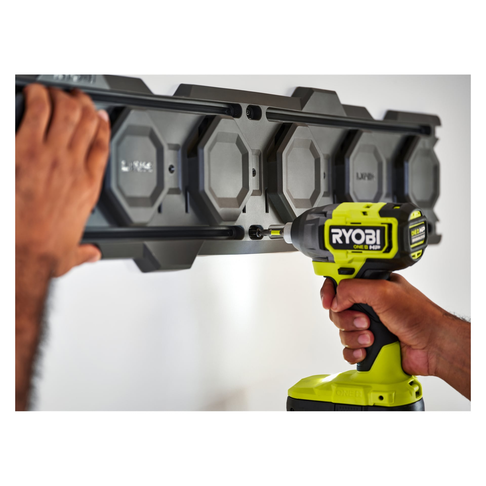 Någon installerar en LINK RSL2WR-2 väggskena (2-pack) med en Ryobi sladdborrmaskin och stabiliserar rälsen med ena handen.