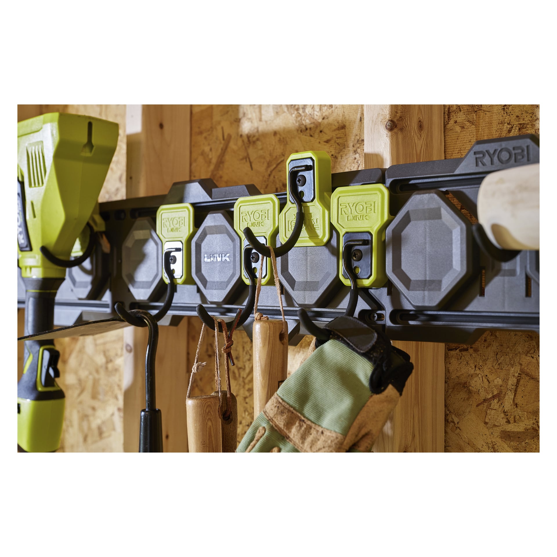 Ryobi J-hook LINK RSLW815 förvaringsställ, svart och grönt, monterat på träväggen, rymmer verktyg och arbetshandskar; Ryobi-loggan synlig.