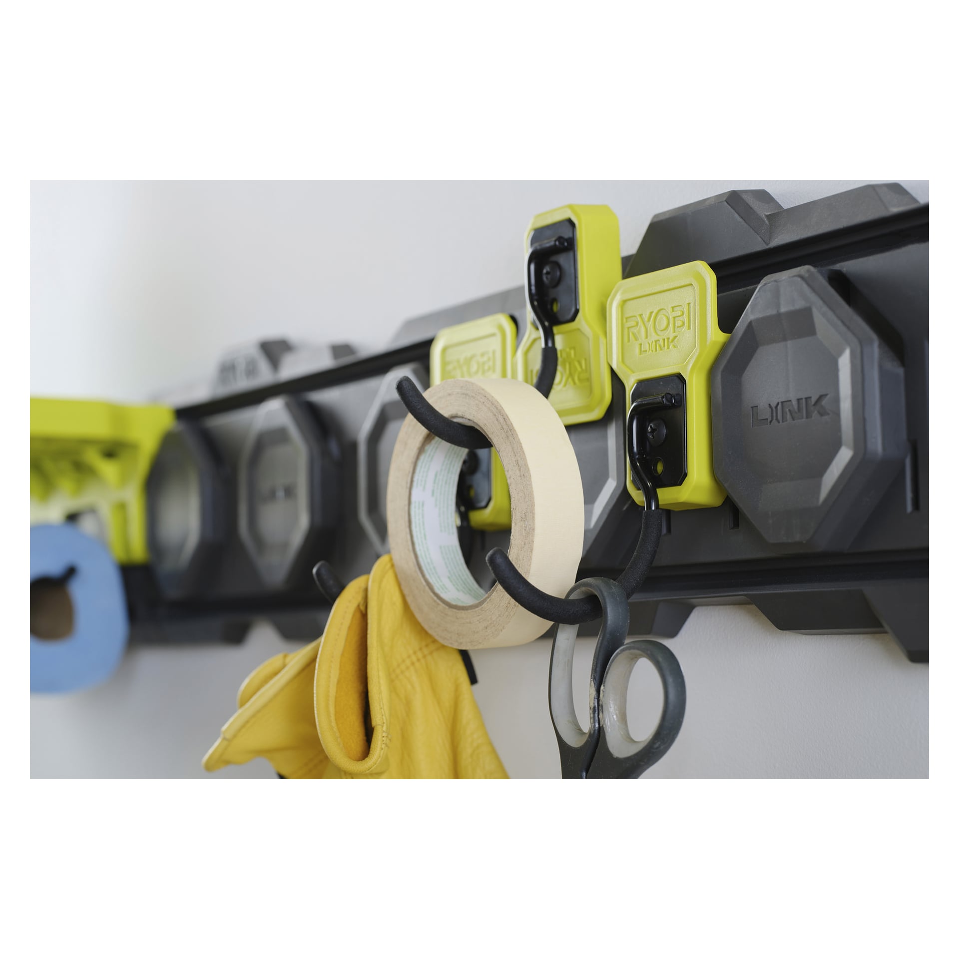 Ryobi J-hook LINK RSLW815, väggmonterad i svart och grått med gula krokar, håller maskeringstejp, gula handskar och sax.