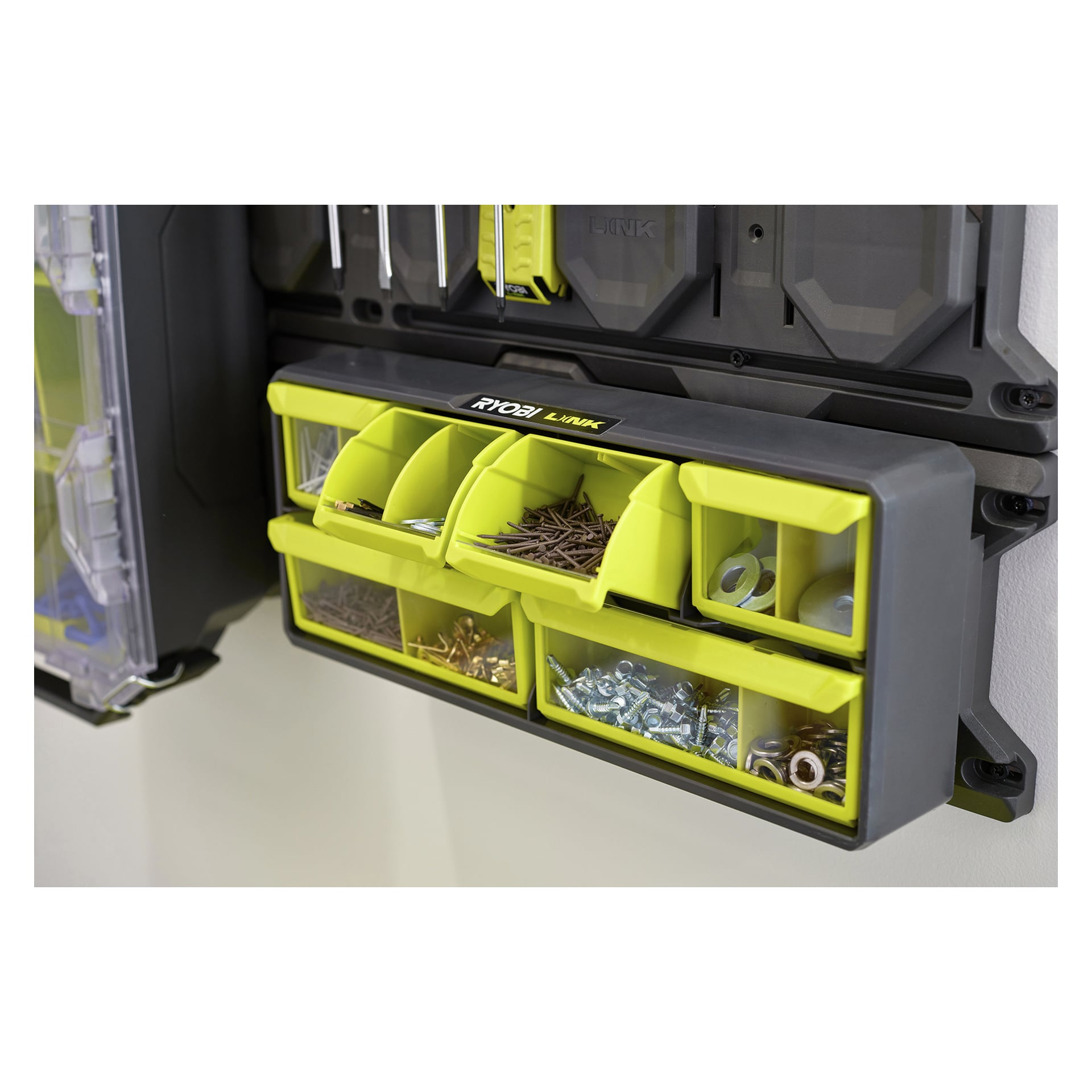 En Ryobi-organisatör med gula och genomskinliga fack på en vägg, som höll sorterade skruvar, spikar, bultar och brickor.