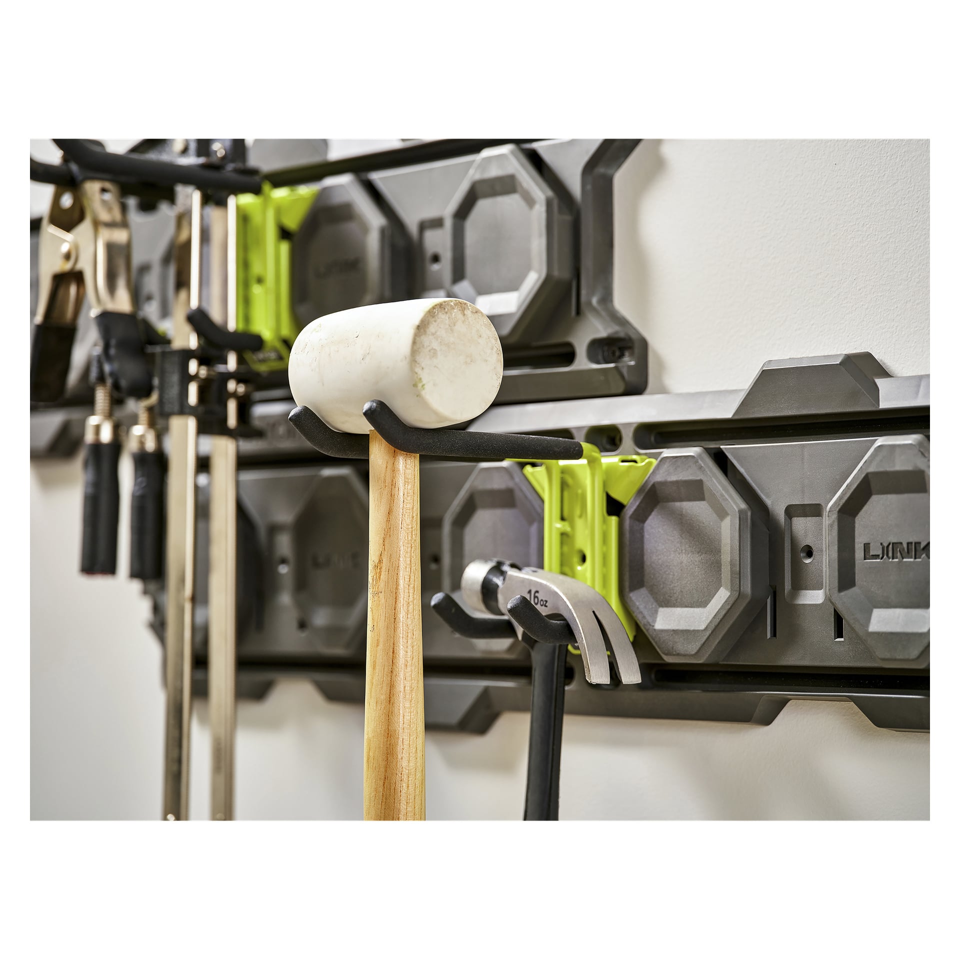 Vit gummiklubba och klohammare hänger på en Ryobi Double Hook LINK RSLW810 förvaringsställ i en verkstad.