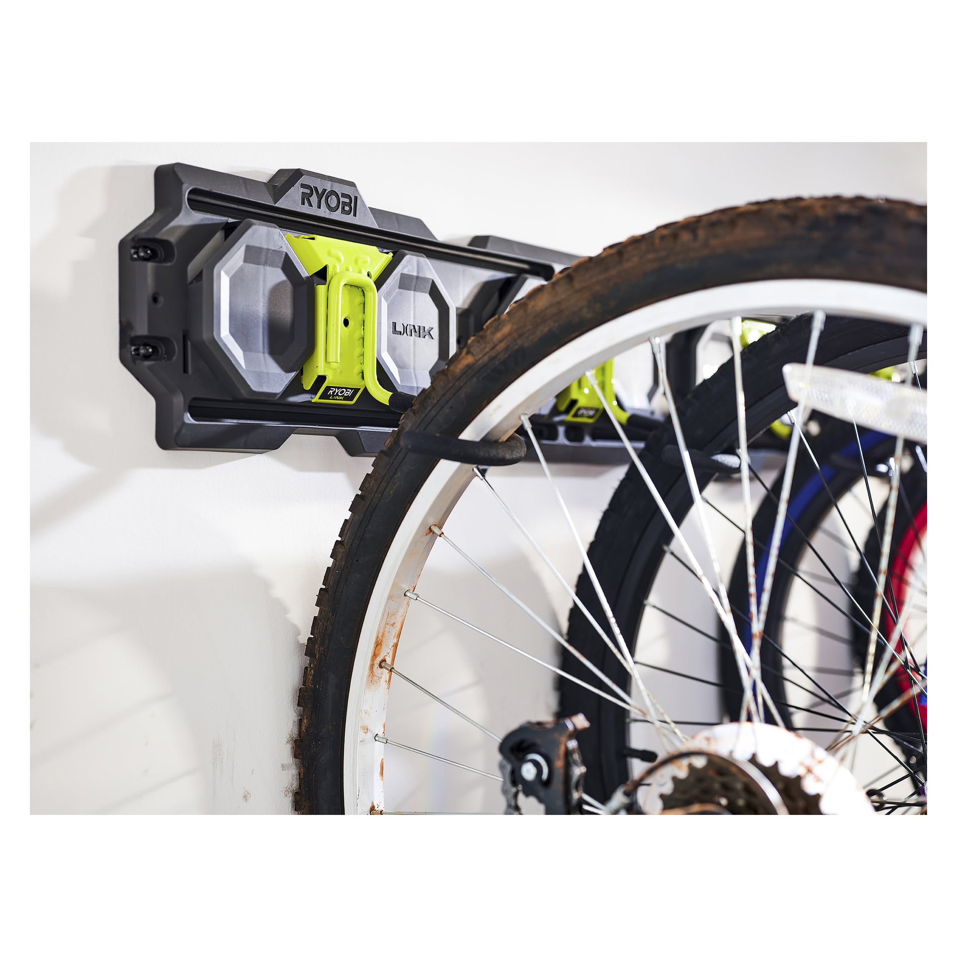Zbliżenie haka rowerowego Ryobi LINK RSLW809 mocno trzyma rower za koła, z oponą i szprychami wyraźnie widocznymi z przodu.
