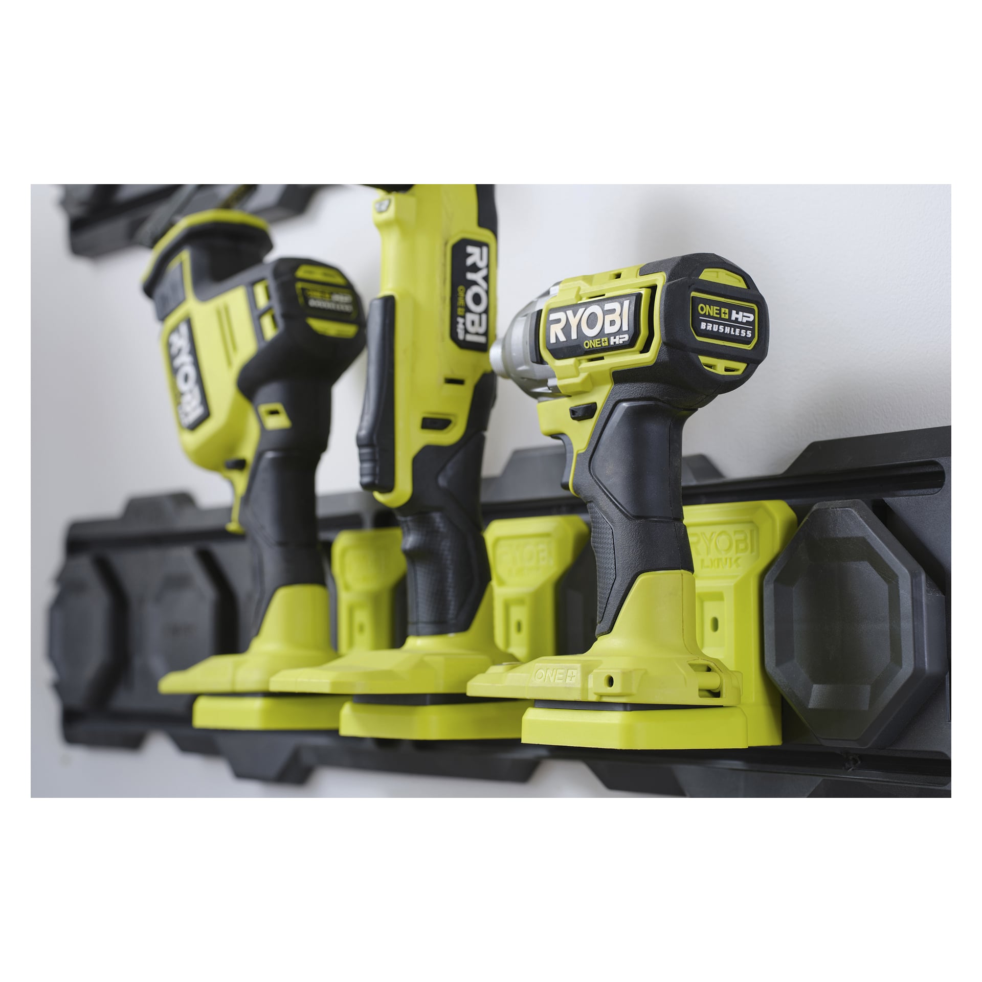 En sladdlös borrmaskin, slagdrivare och bajonsåg från Ryobi ONE+ HP är vertikalt monterade på en svart LINK RSLW817-hållare.
