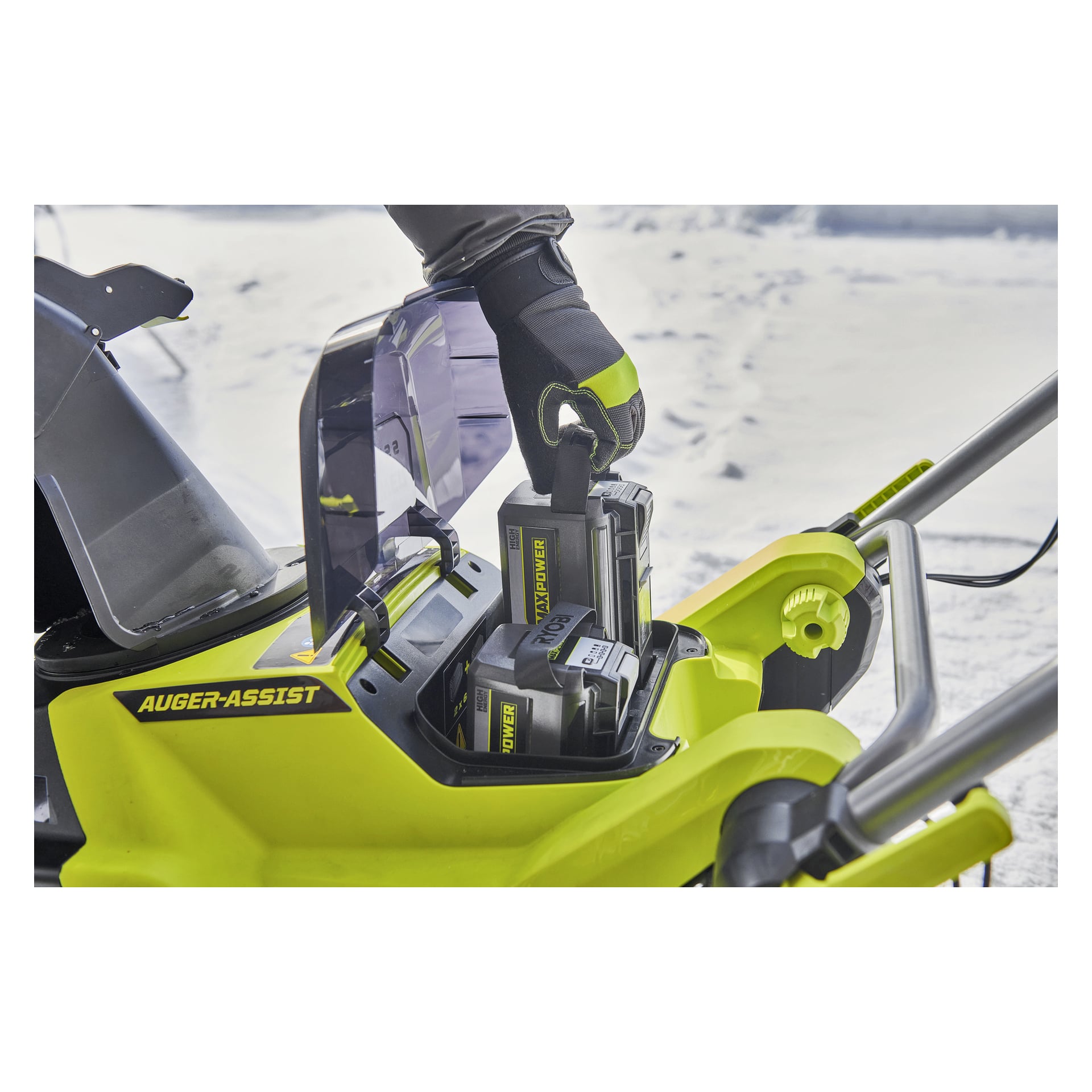 En person med handske placerar ett batteri i en Ryobi Max Power snöslunga RY36STX53B-160 ute på snötäckt mark.