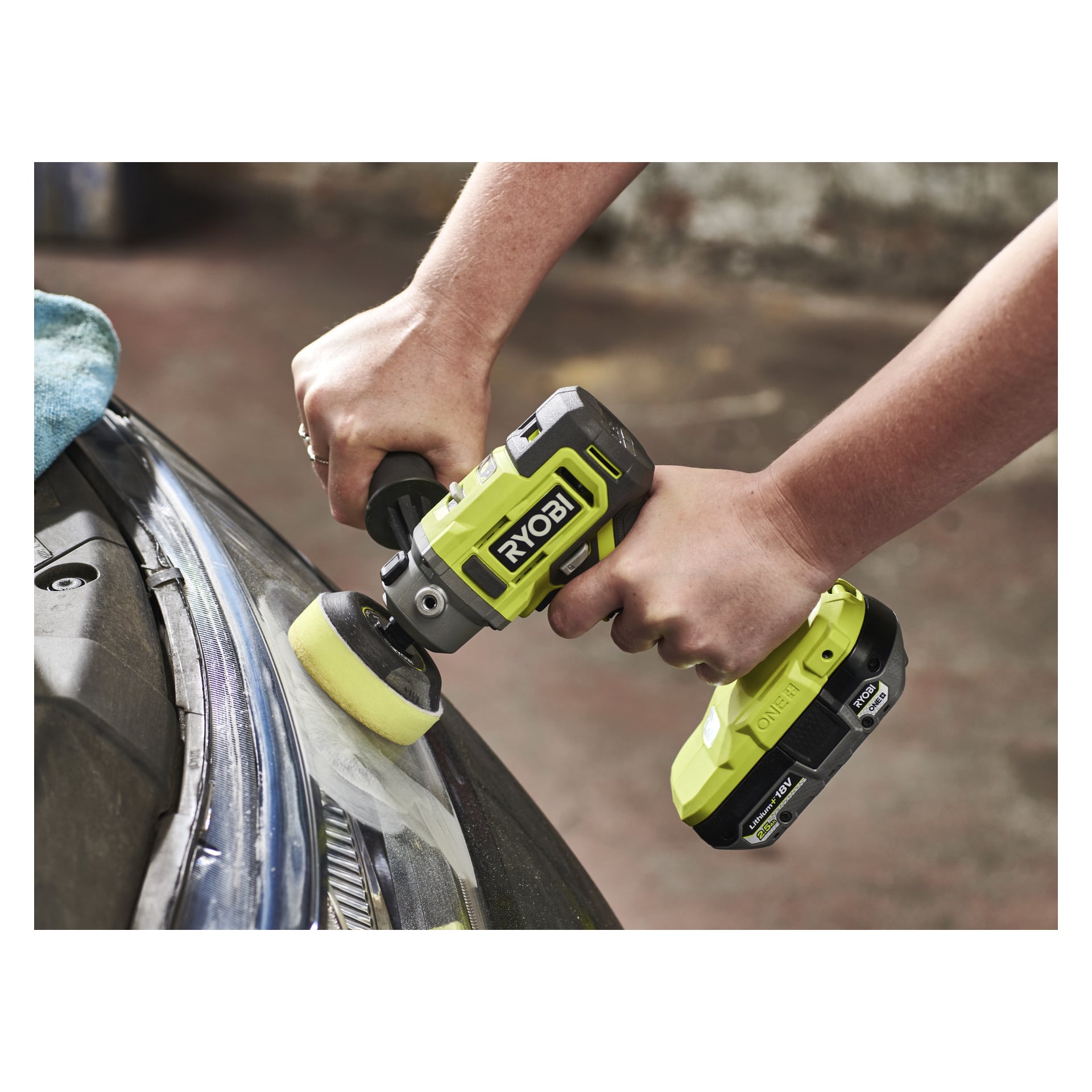 Någon polerar kanten på en bils strålkastare med ett sladdlöst verktyg utrustat med Ryobi One+ Poling Hoodets RADPP75 (4-pack).