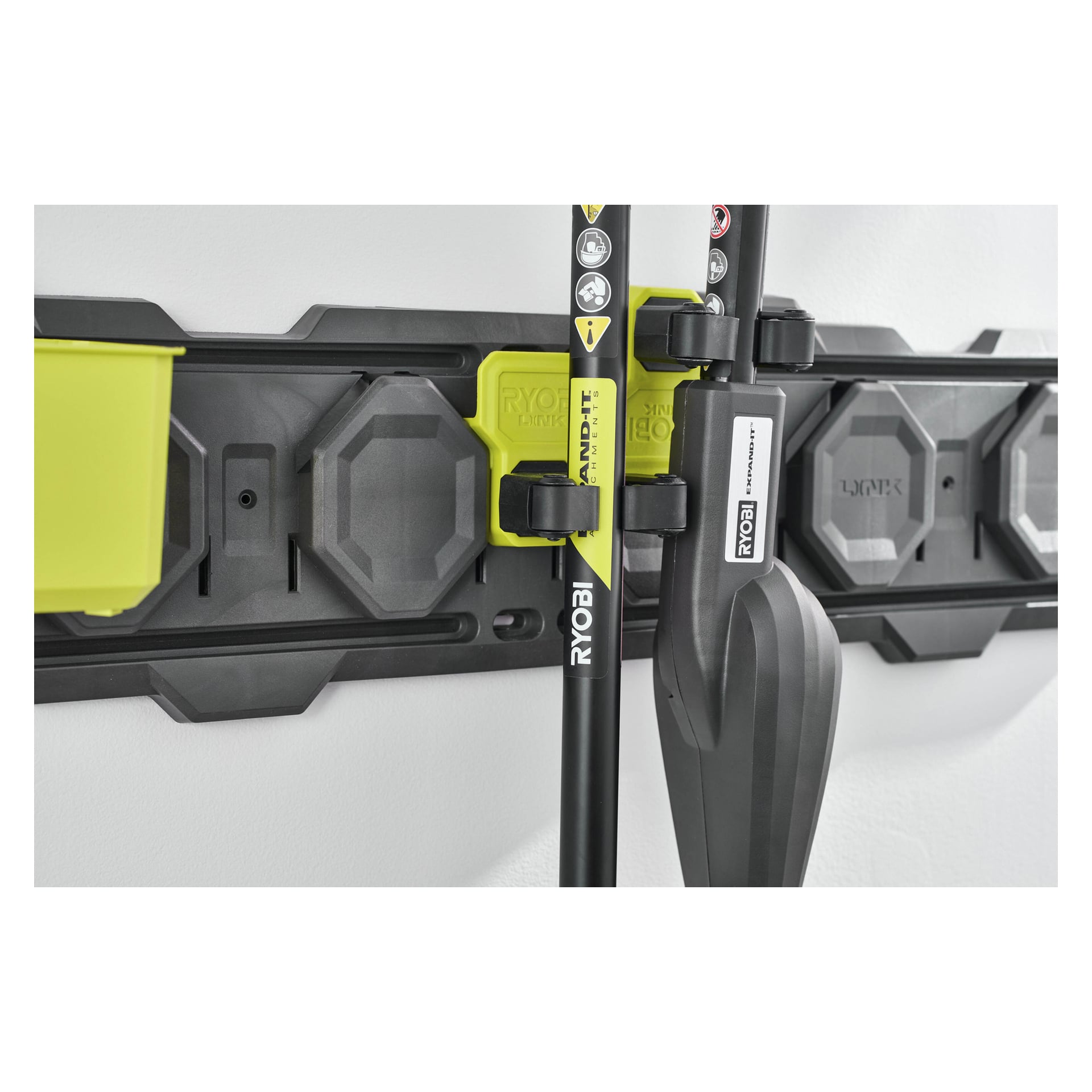 Ryobi Starterkit LINK RSLWPK-8PCJ 8 pieces håller trädgårdsredskap på svarta och gröna krokar, med förvaringsräcket och verktygen monterade på väggen.
