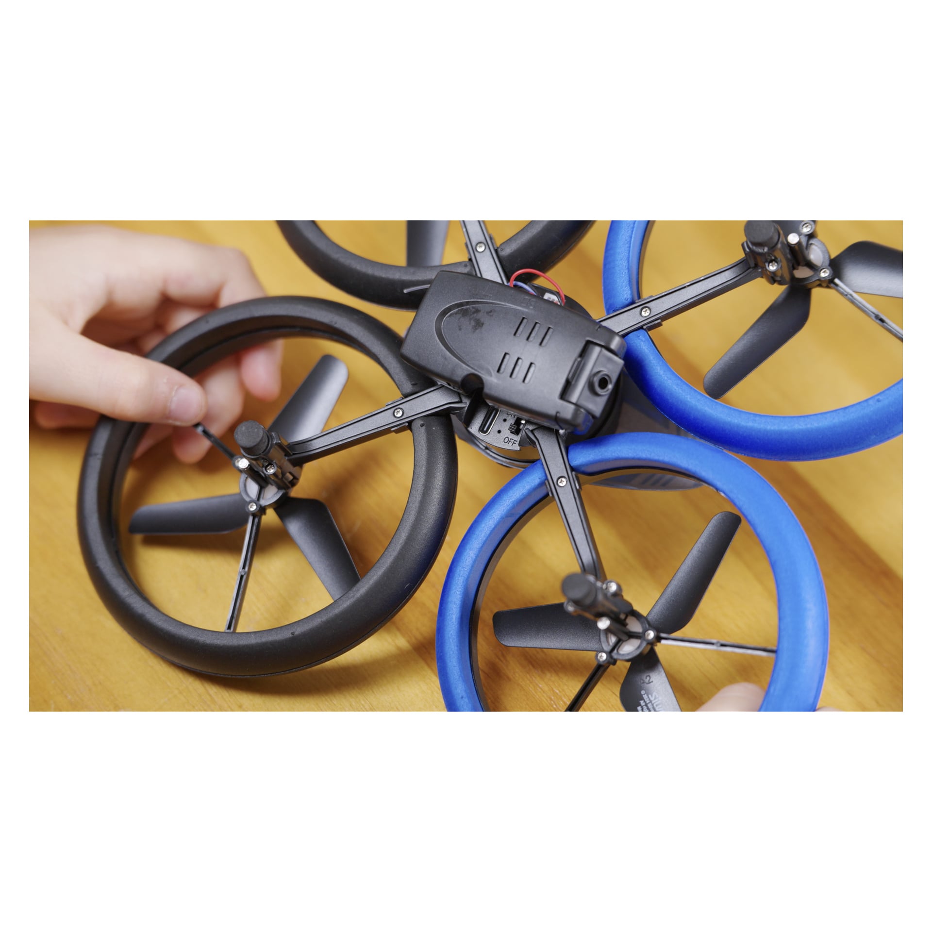 Ręce składają Silverlit Bumper Drone Vision Wifi z niebieskimi i czarnymi osłonami śmigła, baterią i włącznikiem drewna. Wi-Fi, kamera 480p.