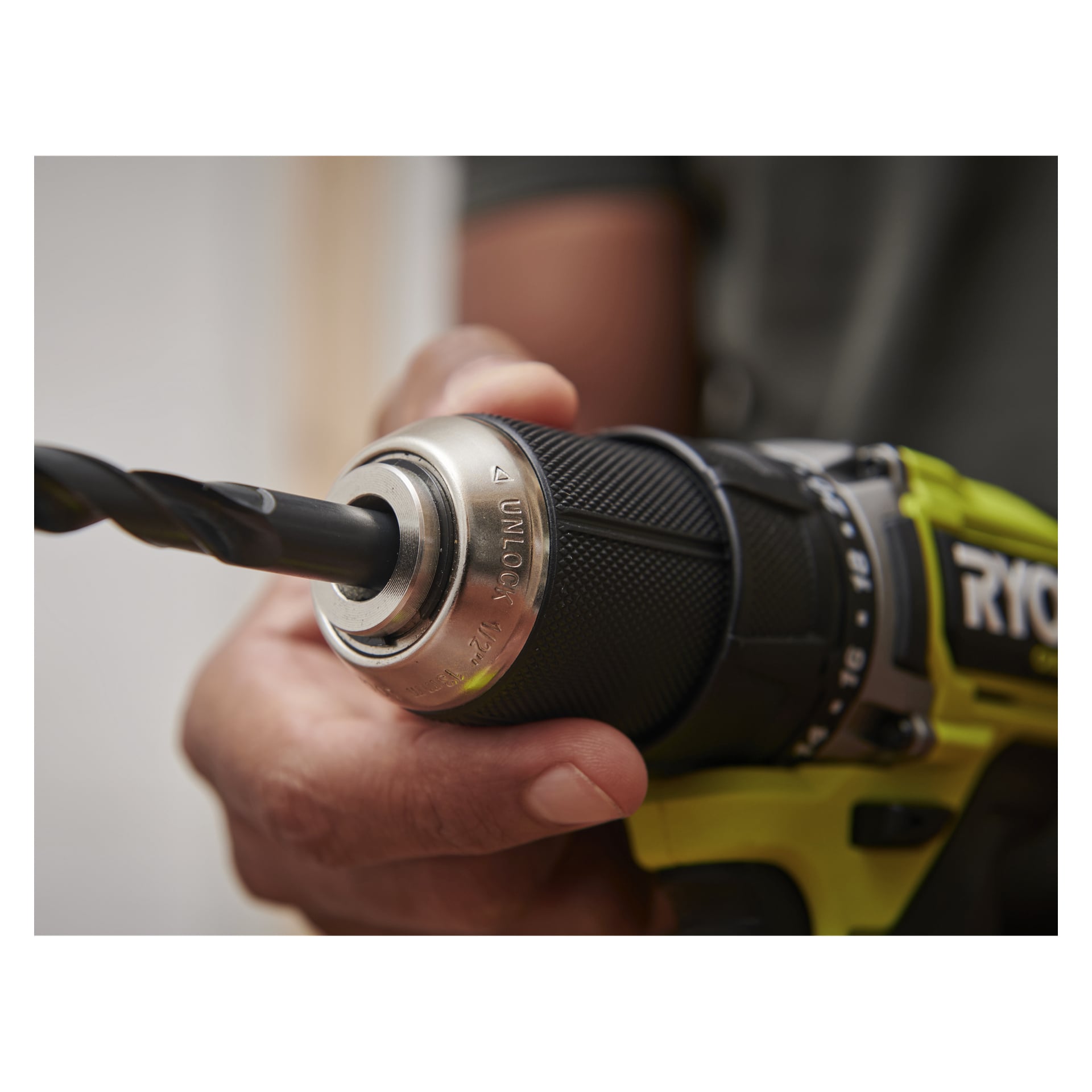 Eine Hand zieht das Korn an einem Ryobi One+ HP Brushless Bohrer mit Batterien und einem Bohrer fest, der in Nahaufnahme gezeigt wird.