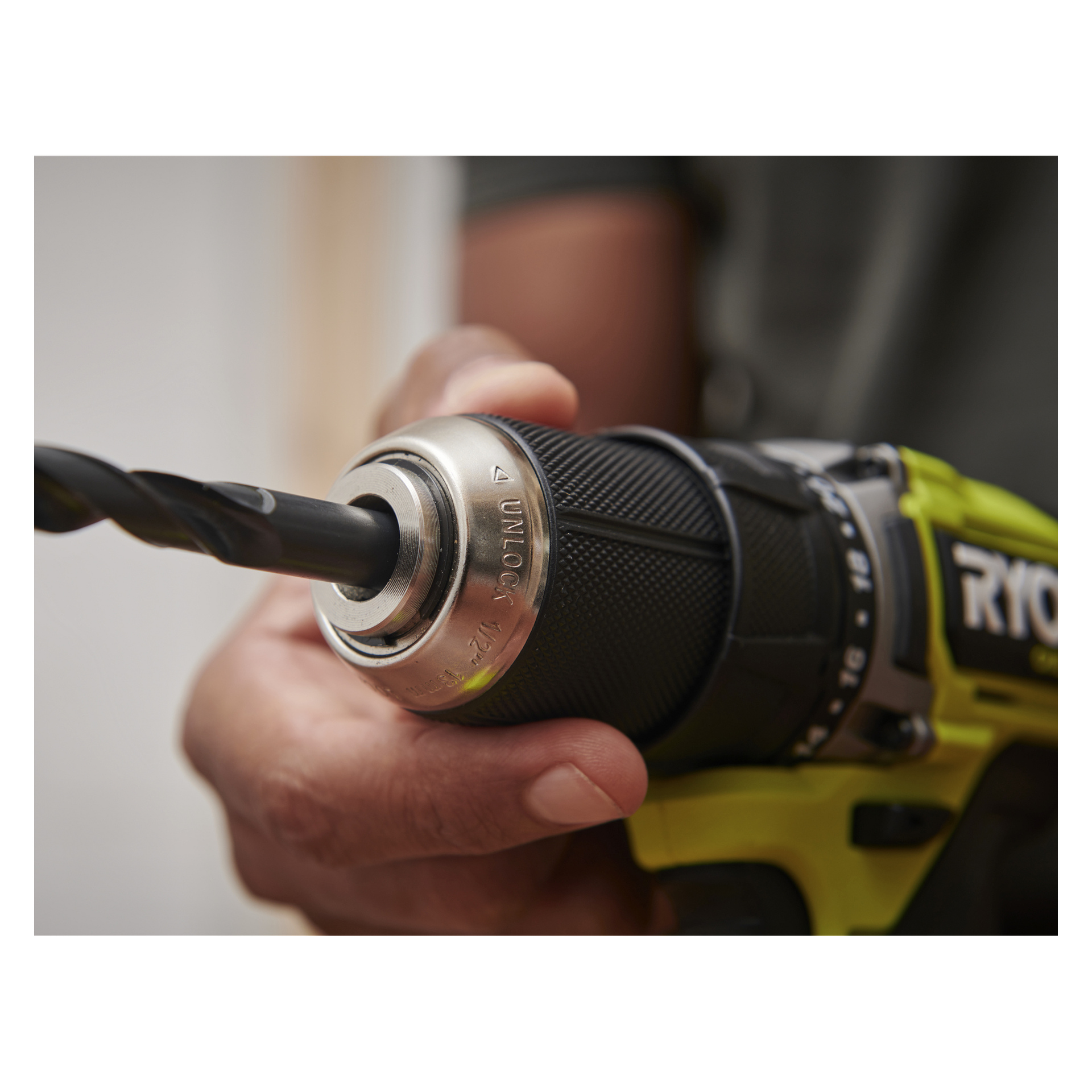 En hand drar åt chucken på en Ryobi One+ HP Brushless borrmaskin med batterier och borr, som visas i närbild.