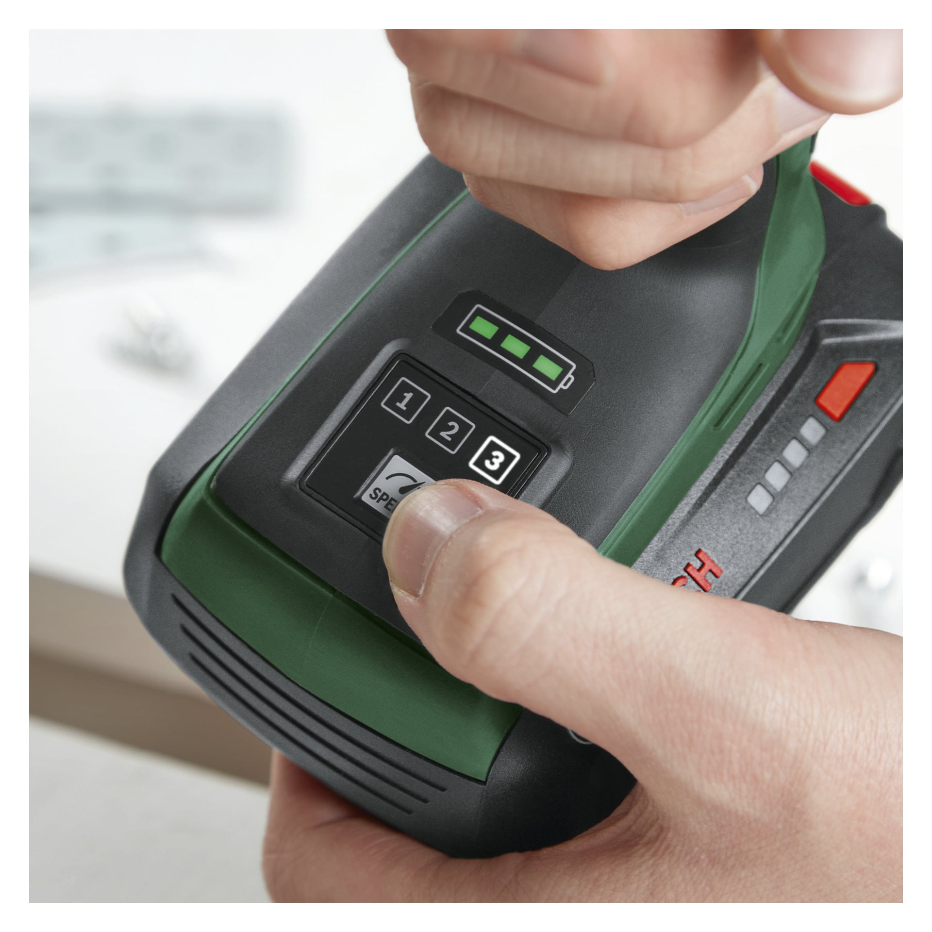 Ręka naciska przycisk "2" na czarno-zielonym Bosch UniversalImpactDrive 18V-350, pokazując trzy z czterech listwek baterii.