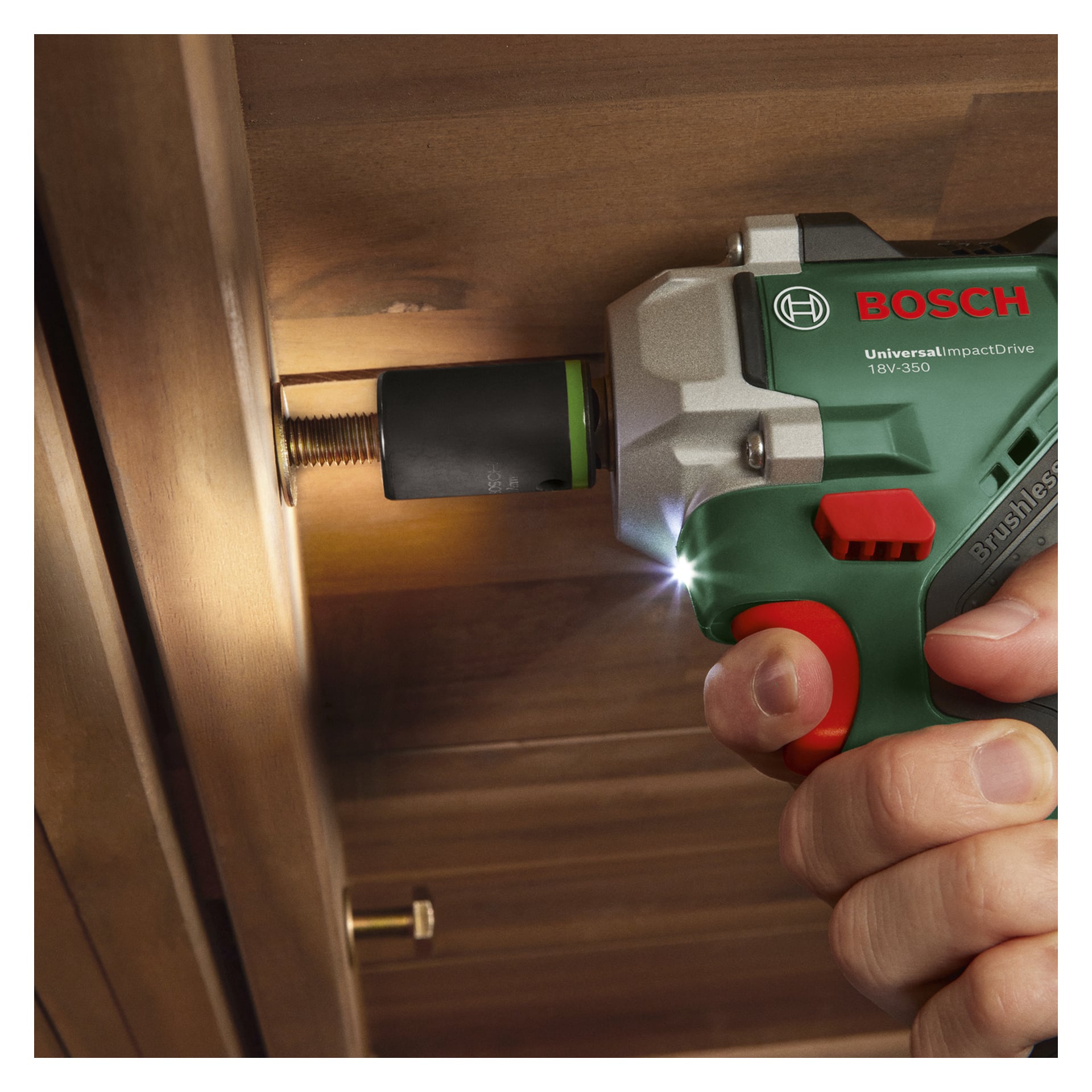 Osoba używa klucza Bosch Power 4 All UniversalImpactDrive 18V-350, aby podkręcić śrubę pod drewnem, a dioda LED oświetla ten obszar.