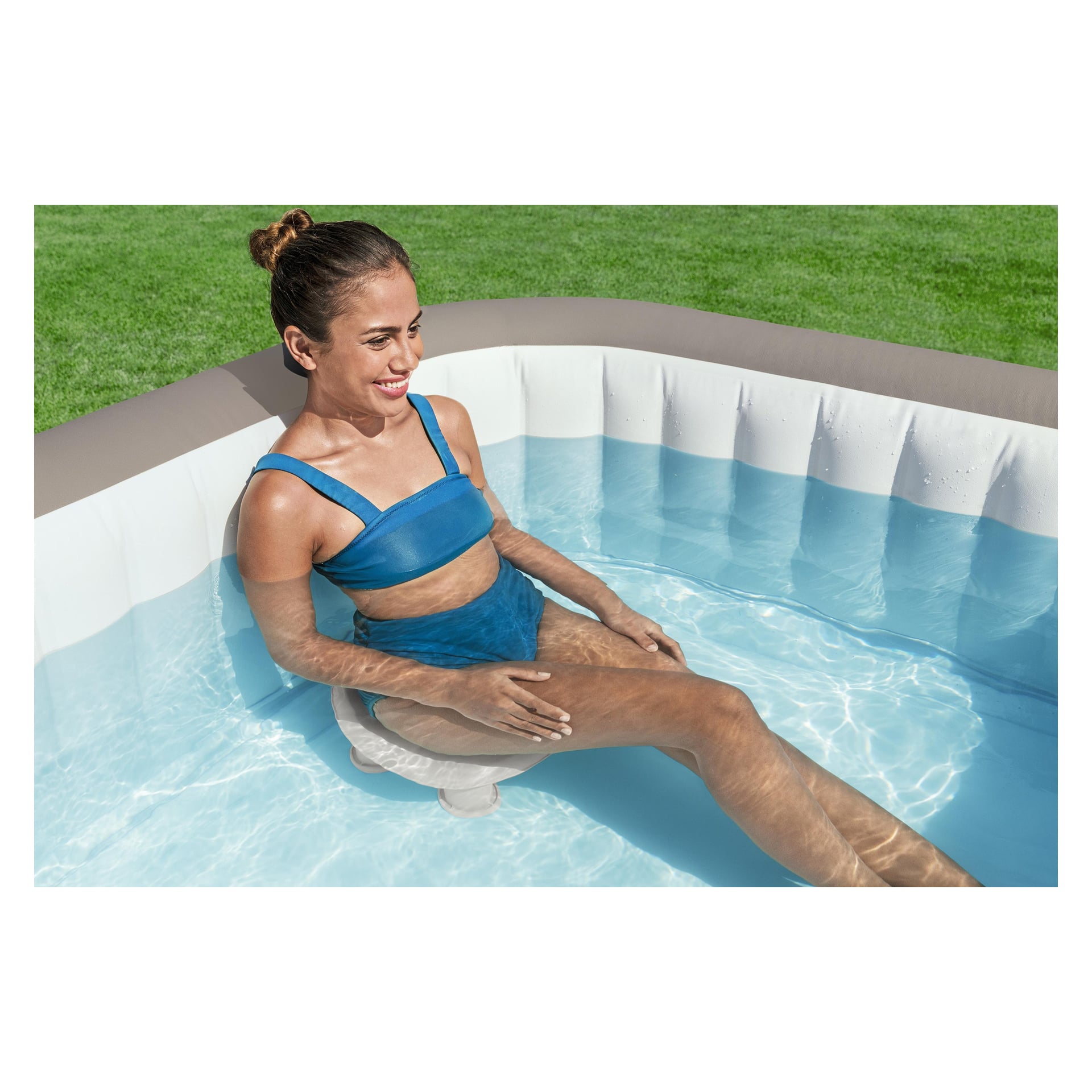 En kvinna slappar i en Bestway LAY-Z-SPA-stol och njuter av solen i en klar uppblåsbar pool på en grön gräsmatta.