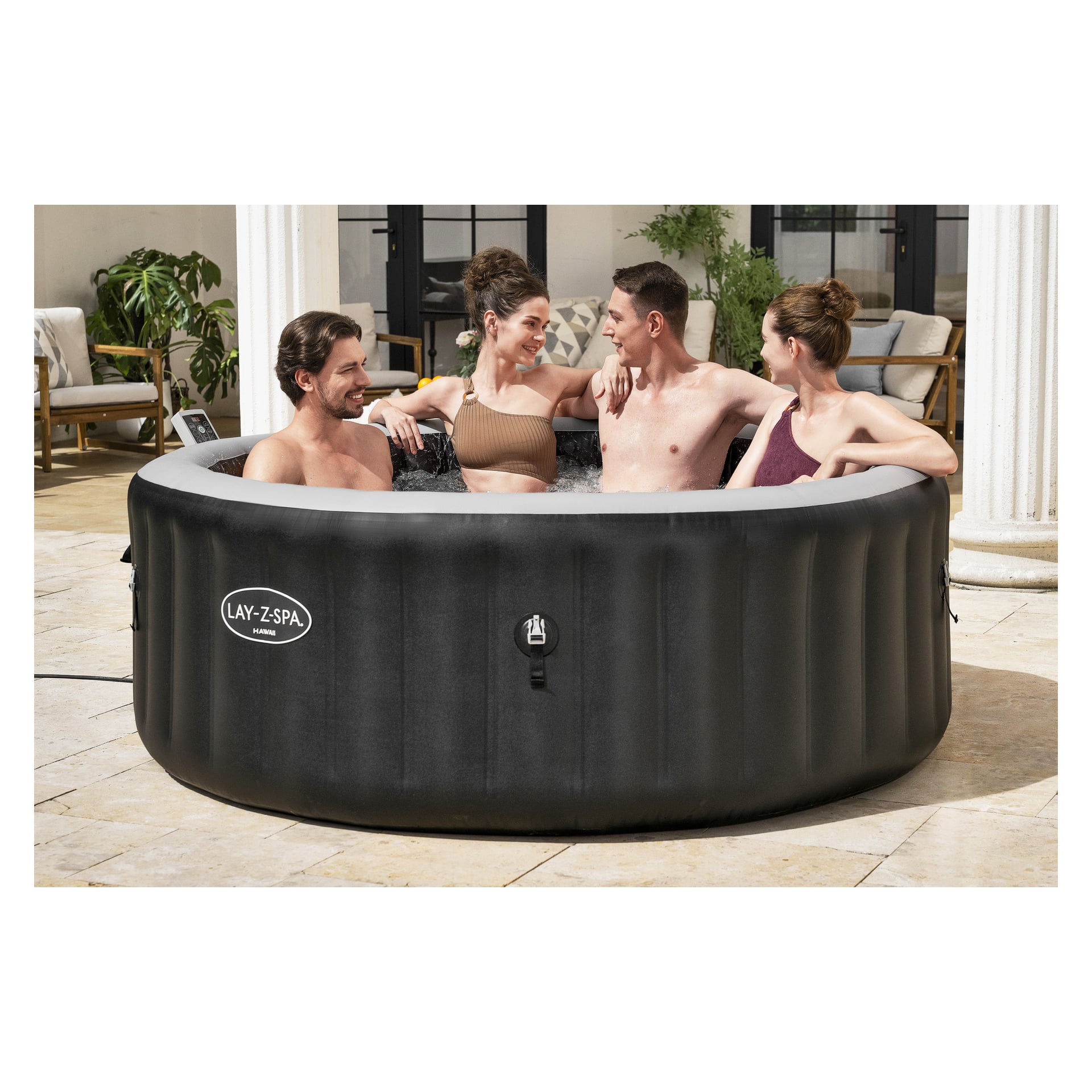 Fyra leende vuxna kopplar av i en bubblande Lay-Z-Spa-bubbelpool på en stenterrass, omgiven av frodiga växter och utemöbler.
