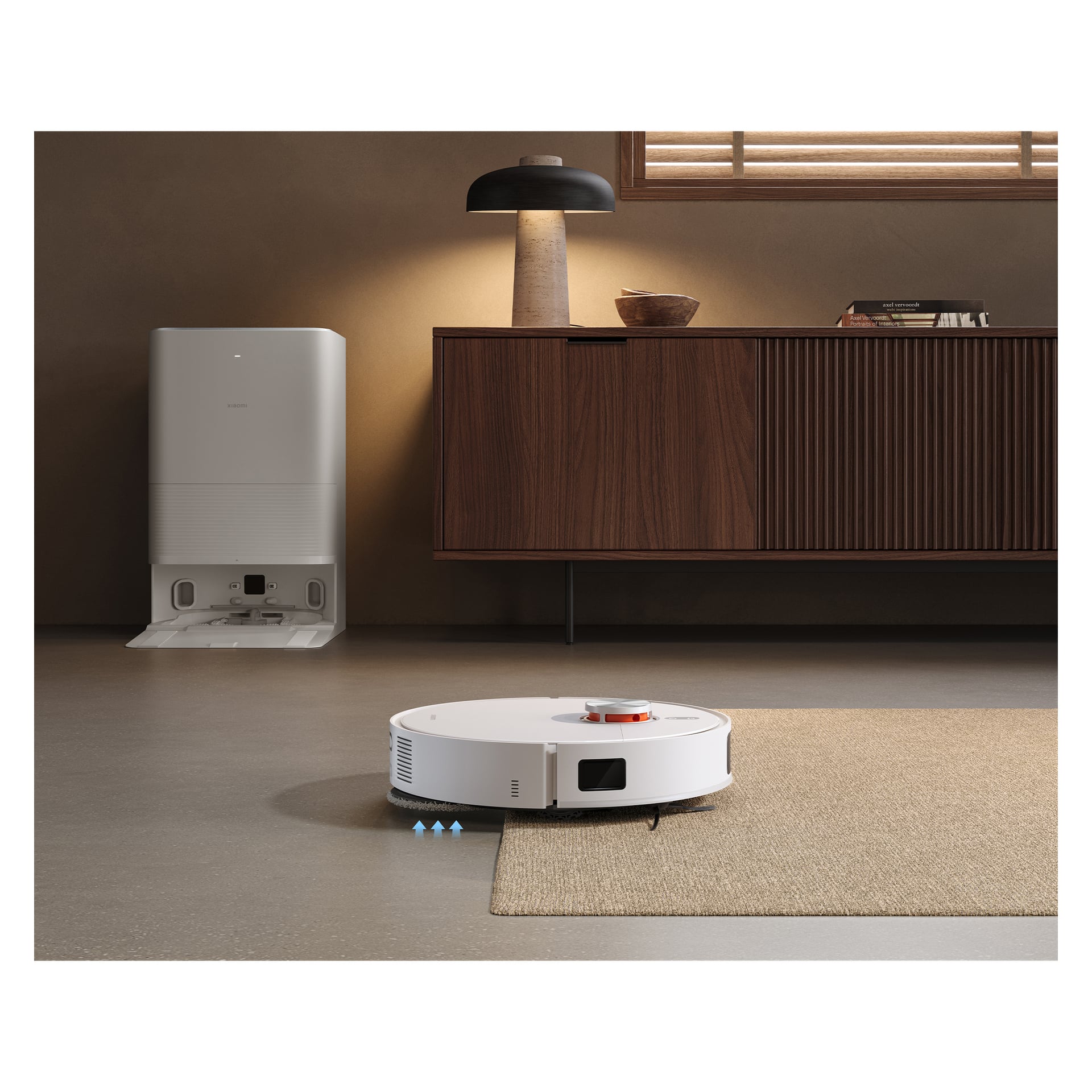 Biały odkurzacz Xiaomi Robotic, "X20 Pro", czyści podłogę obok dywanu w stylowym salonie. Stacja dokowania znajduje się w pobliżu, a w tle widać drewnianą szafkę z lampką stołową. Światło słoneczne wpada przez okno z drewnianymi żaluzjami.