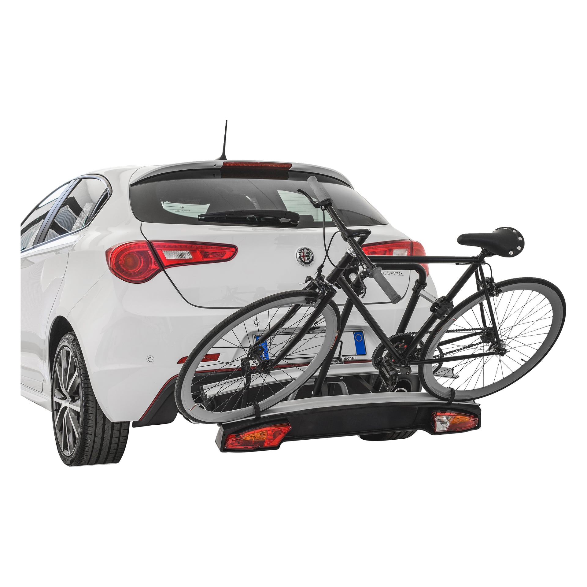 En svart sykkel står på en Hamron tilhengerstang festet til en hvit hatchback, med baklys og skiltholder, sett fra bakvenstre bak.
