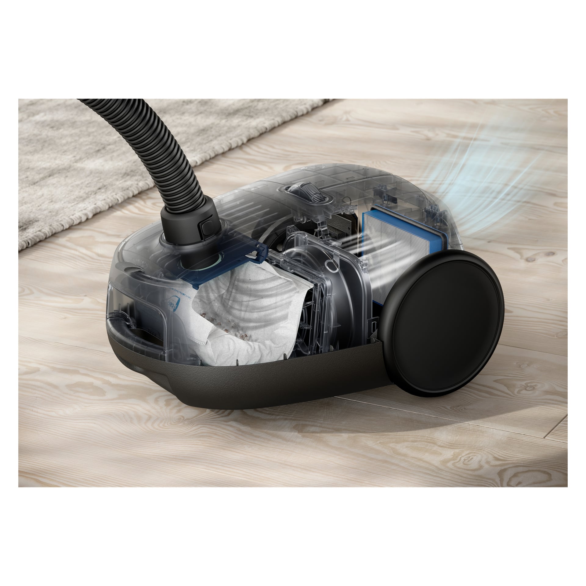 Electrolux Clean 600-dammsugare med genomskinligt fodral visar dammpåse, filter och slang på trägolvet vid en matta; Blå linjer visar luftflödet.