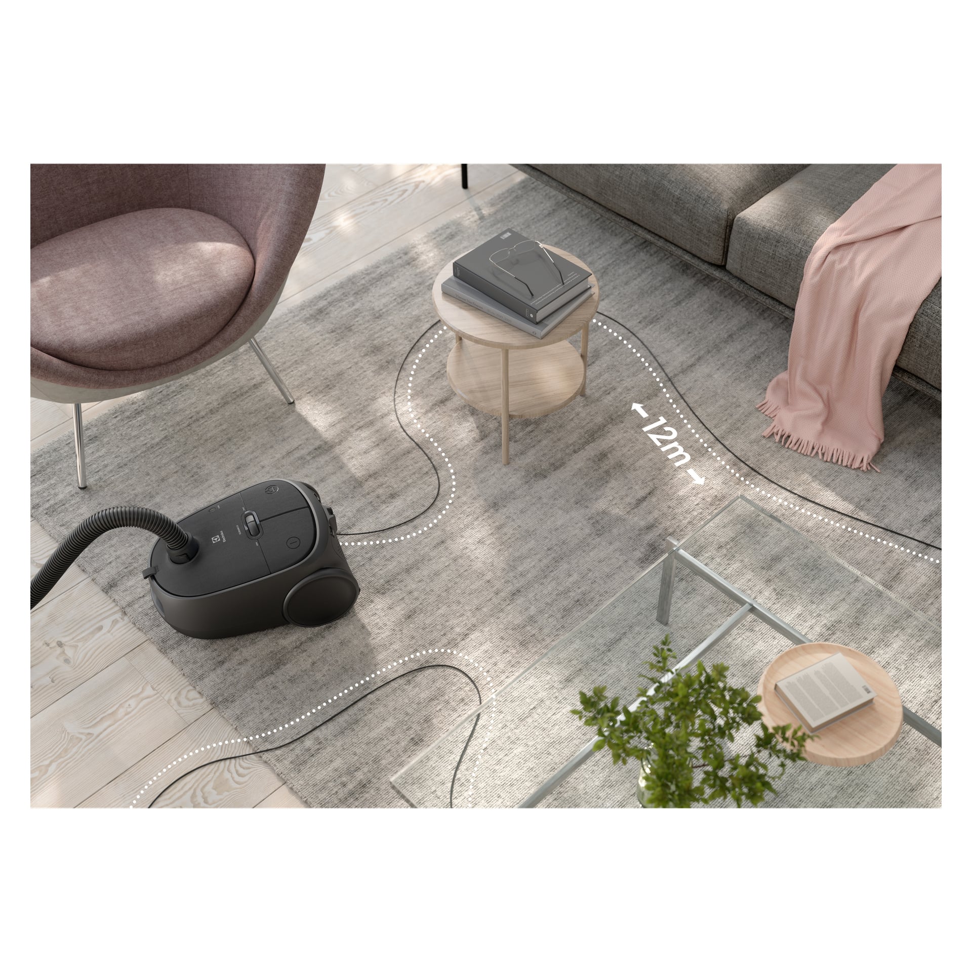 Electrolux Clean 600-dammsugaren står på en grå matta mellan en rosa stol, ett glasbord och en soffa med rosa filt; 12 meters räckvidd visas.