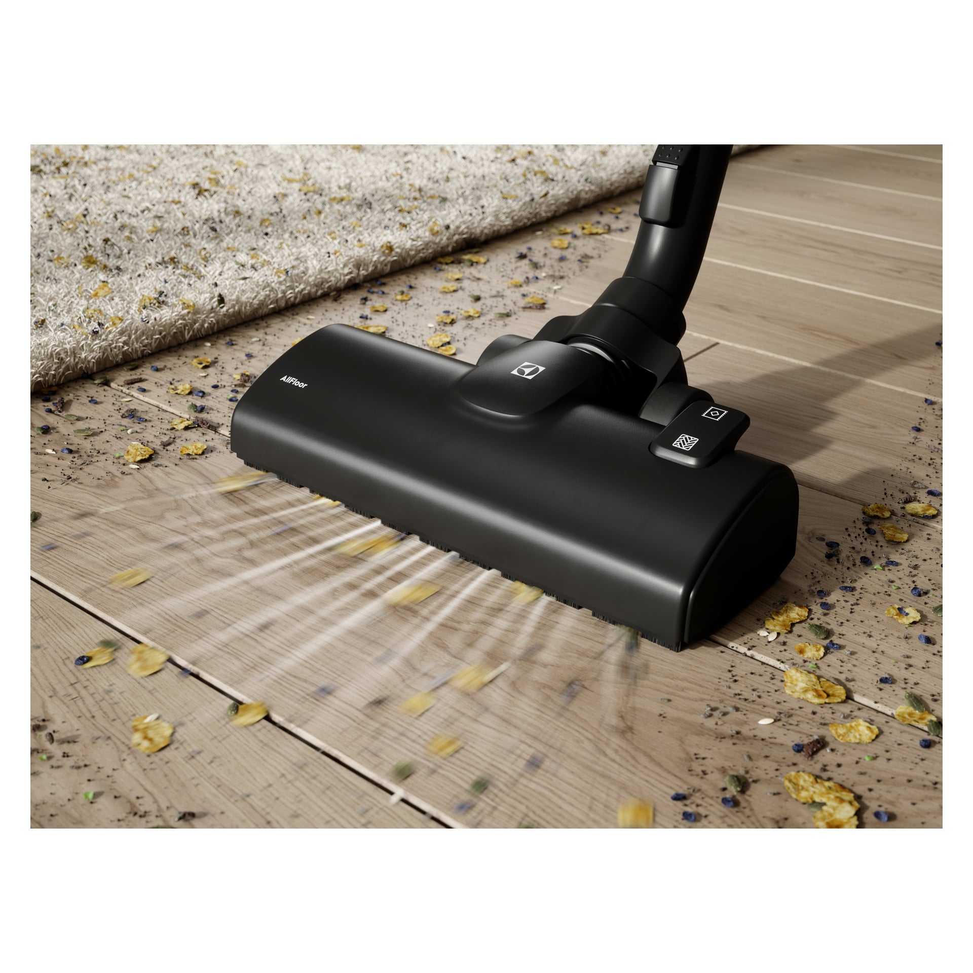 Electrolux Clean 500 EB51C1OG odkurza okruchy i zanieczyszczenia z drewnianej podłogi obok dywanu, wykazując silne ssanie.