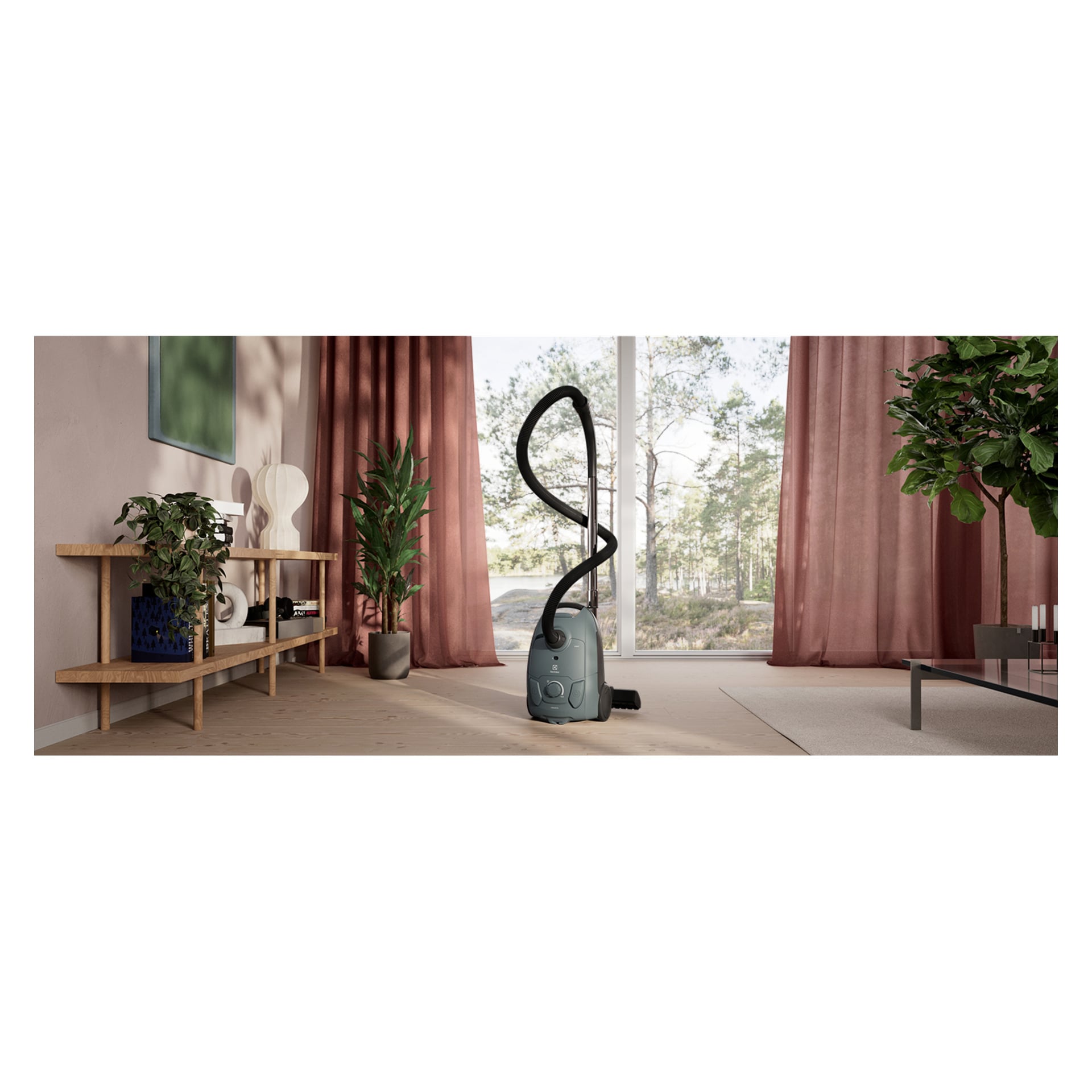 Odkurzacz Electrolux Clean 500 EB51C1OG z zakrzywionym wężem stoi na lekkiej drewnianej podłodze w salonie z różowymi zasłonami i roślinami.