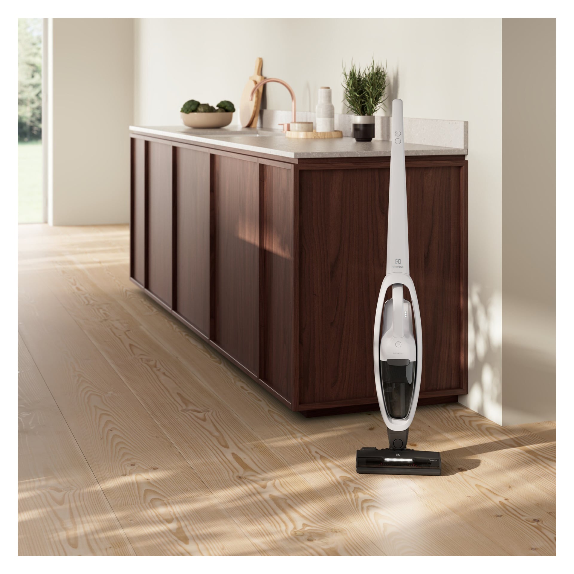 En Electrolux Upright Vacuum Cleaner 500 Clean står ved siden av en mørk trekjøkkenøy med en lys topp i et lyst, nøytralt rom.
