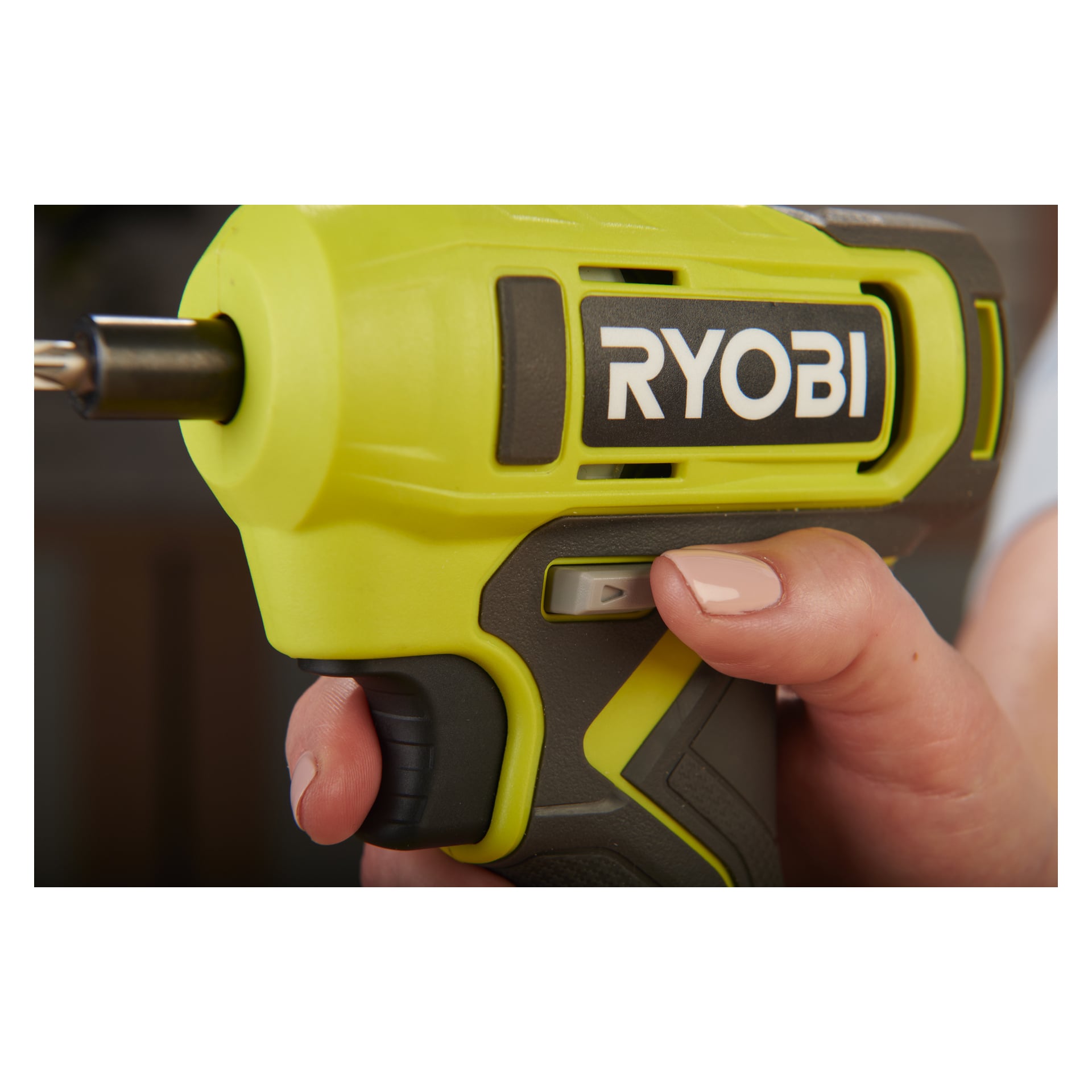 Ręka człowieka obsługuje śrubokręt Ryobi One+ RSD18-0, kciuk naciska szary przycisk na zielono-czarnym narzędziu.