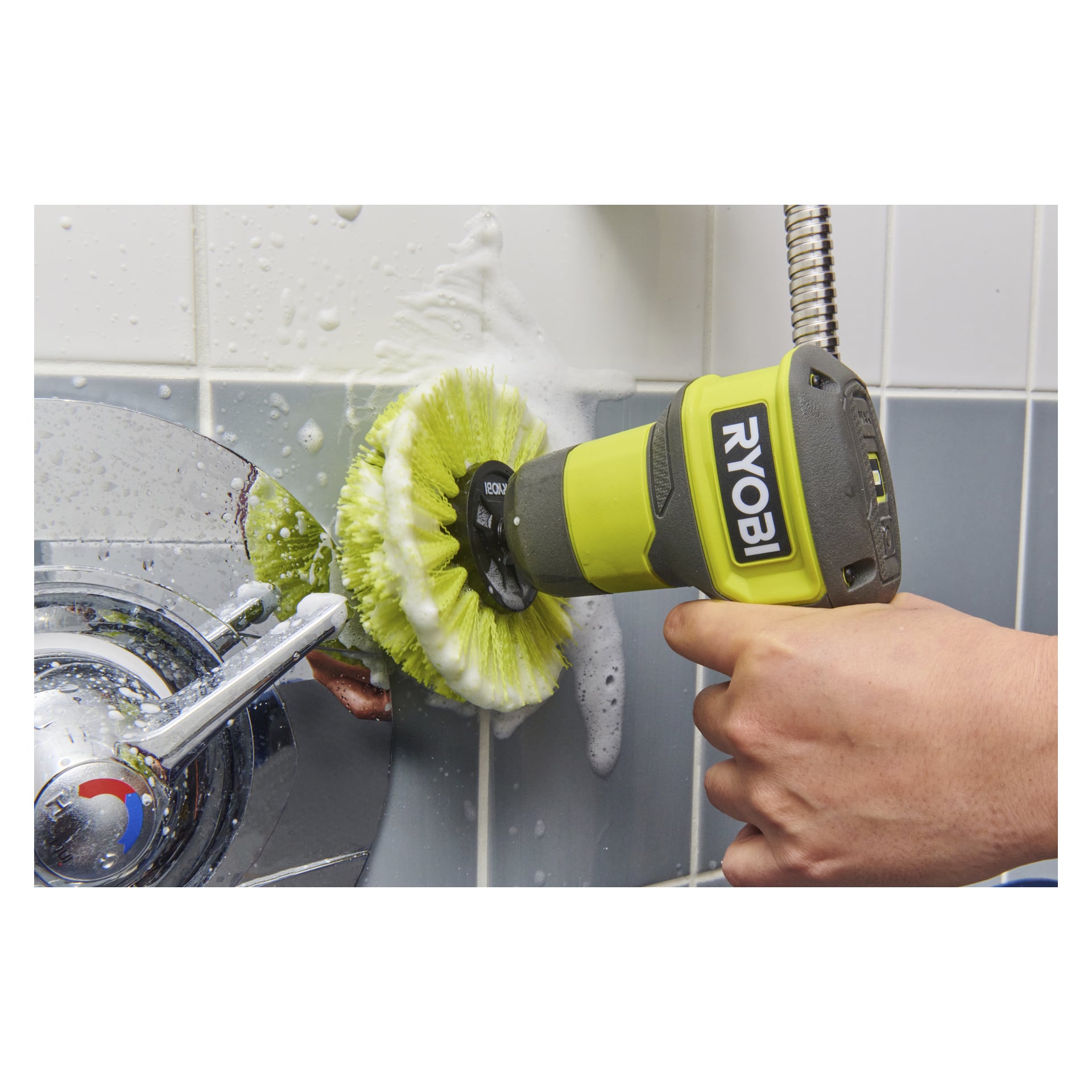 Någon rengör en kaklad badrumsvägg och en kromad duscharmatur med en Ryobi RACLRM110 USB-litiumborste, tvållödder synliga.