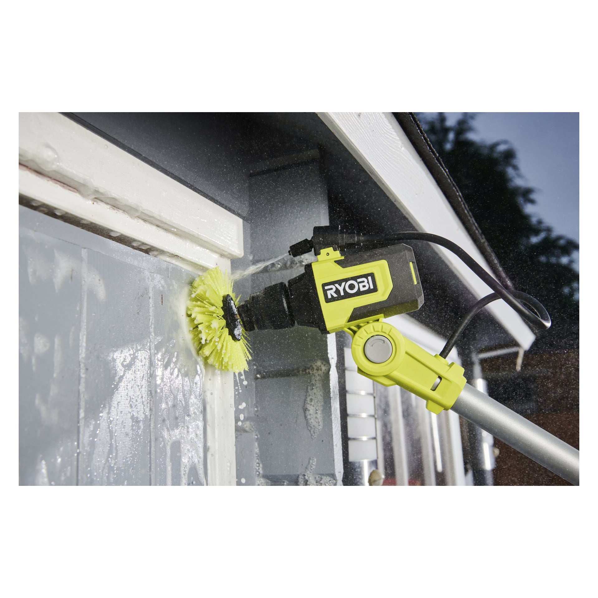 En Ryobi USB Lithium Cleaning RACLRM110 med gult borsthuvud skrubbar grå utvändig huslist och sköljer bort smuts och smuts.