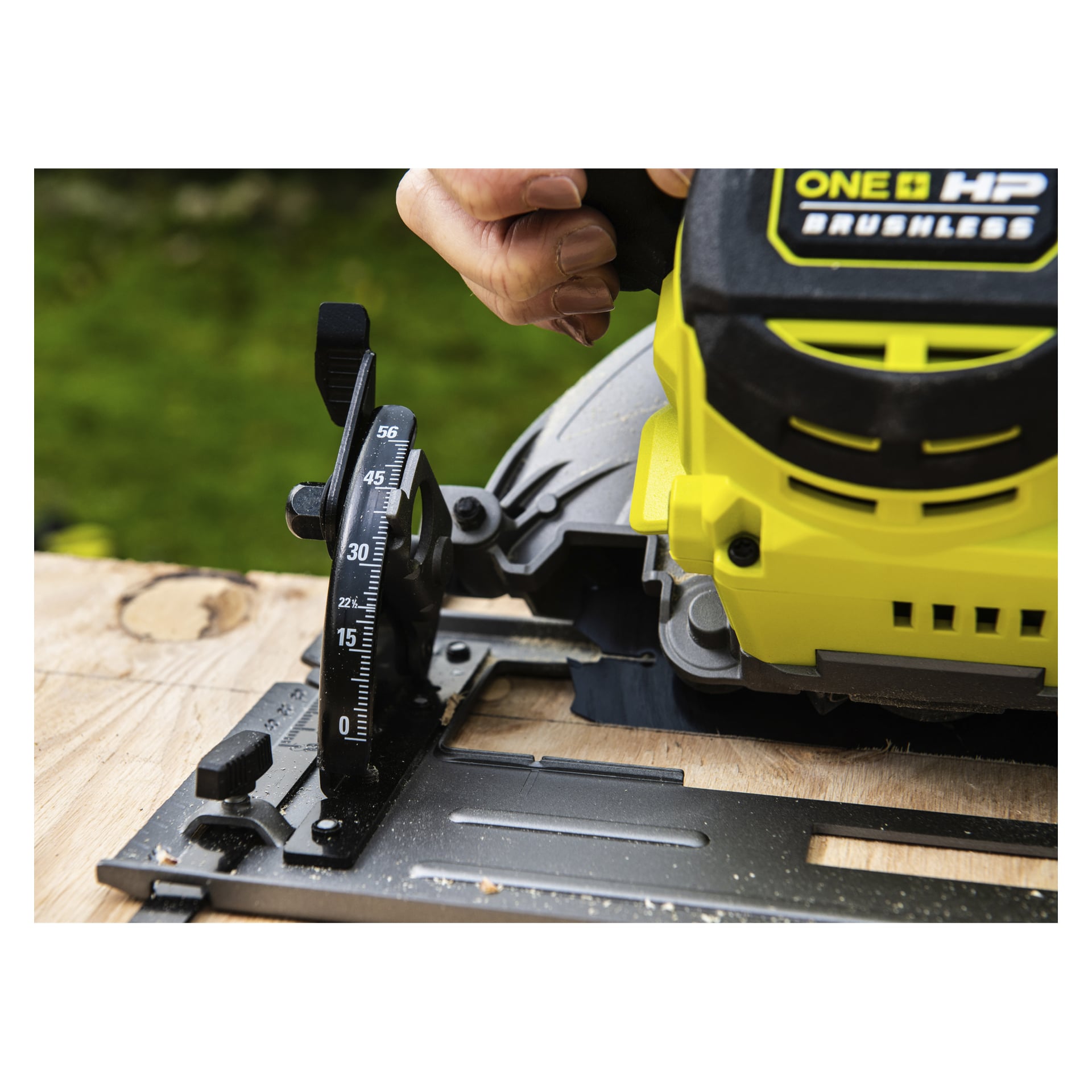 Man finjusterer vinkelmåleren på en gul Ryobi One+ HP rundsag RCS18X1-0, som er plassert på utendørs tre.