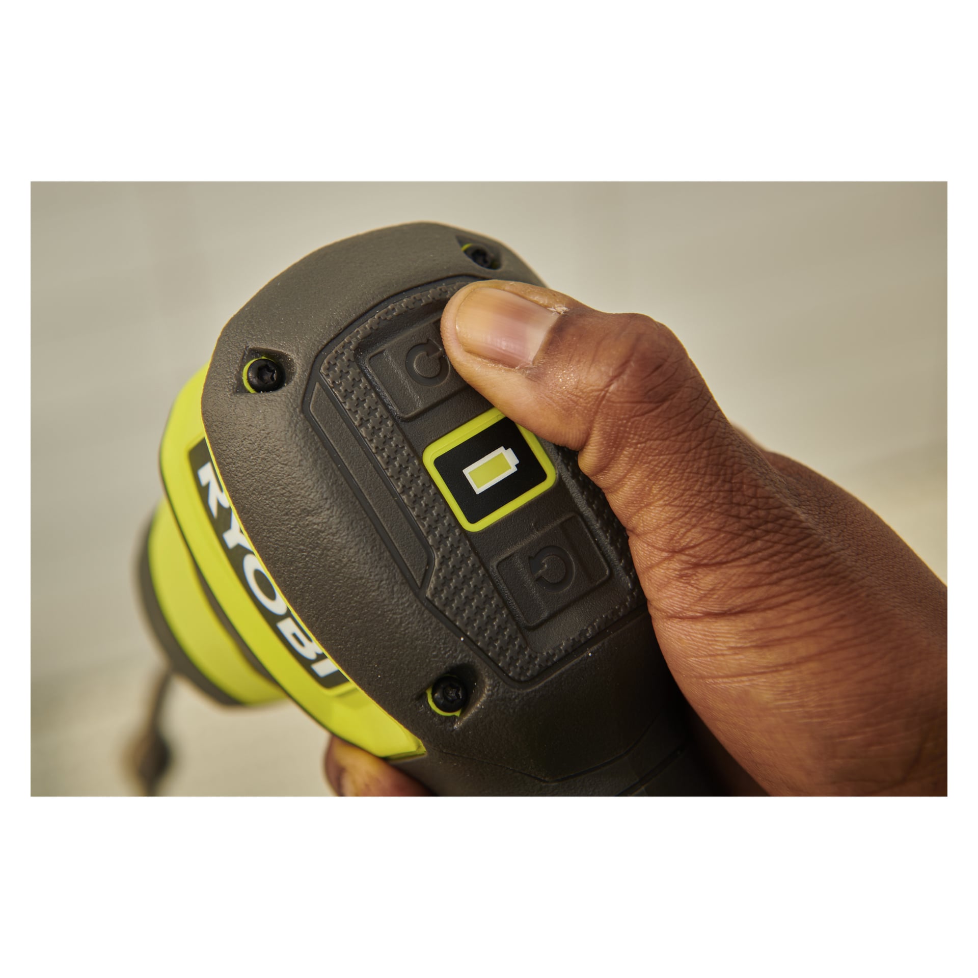 En hånd trykker på en knapp på Ryobi USB Lithium drain cleaner RDA4-0, og fremhever batteriindikatoren på det svarte og gule huset.