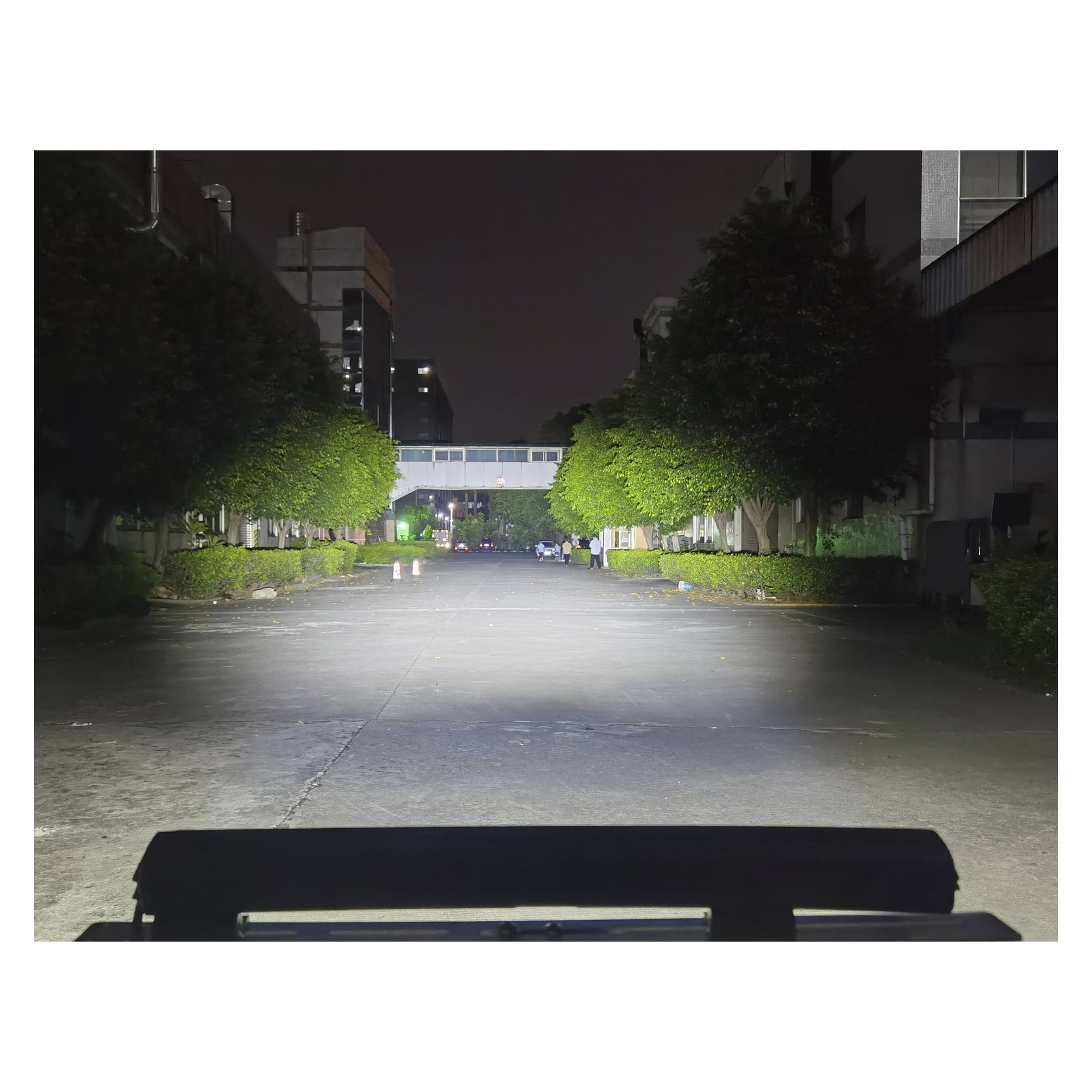 En nattgata som lystes upp av Hamron Light bar LEDs, kantad av träd och byggnader i fjärran.