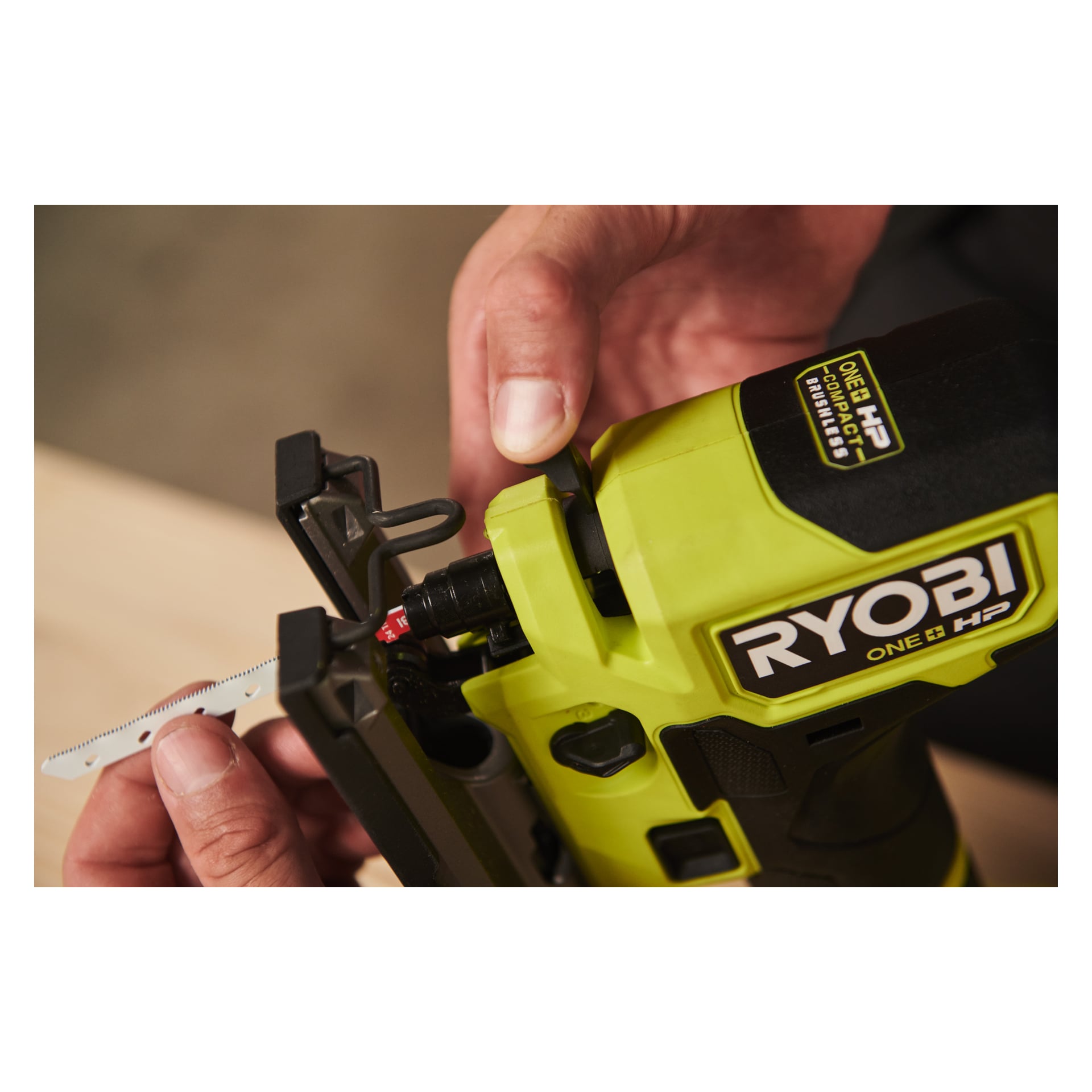 Osoba wkłada brzeszczot do żółto-czarnego elektronarzędzia Ryobi One+ HP. Ręce trzymają zarówno brzeszczot, jak i narzędzie, pokazując proces z bliska.
